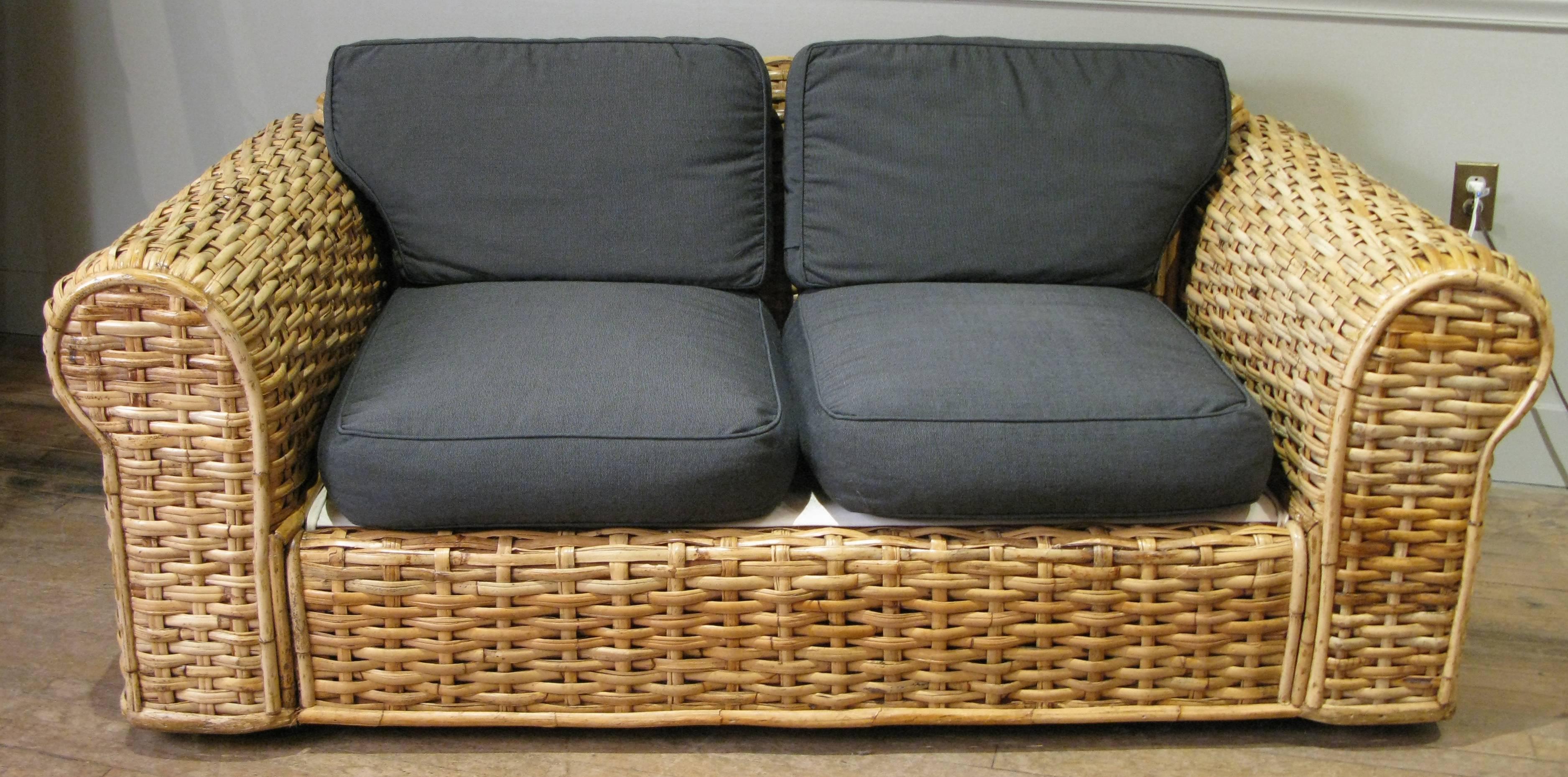 A beautiful and gracious two-seat sofa or settee by Ralph Lauren Home, in large-scale woven rattan. Extremely well made and very comfortable, the cushions have two sets of covers, a dark grey woven file, and a set of white cotton duck covers, both