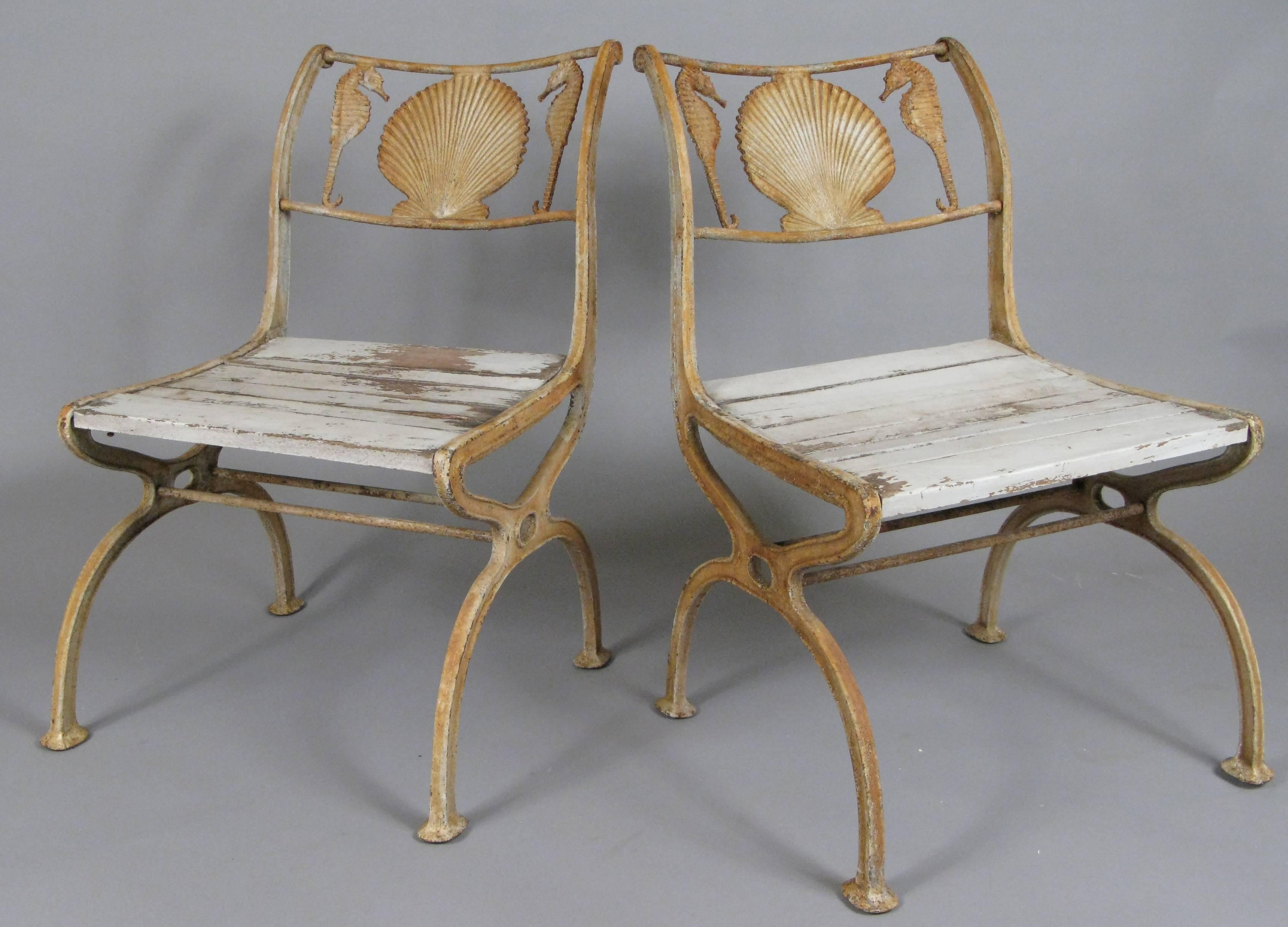 A pair of antique 1920s cast iron chairs with a seashell and seahorse motif in the curved frieze on the back of the chair. wonderful scale and in original condition. 