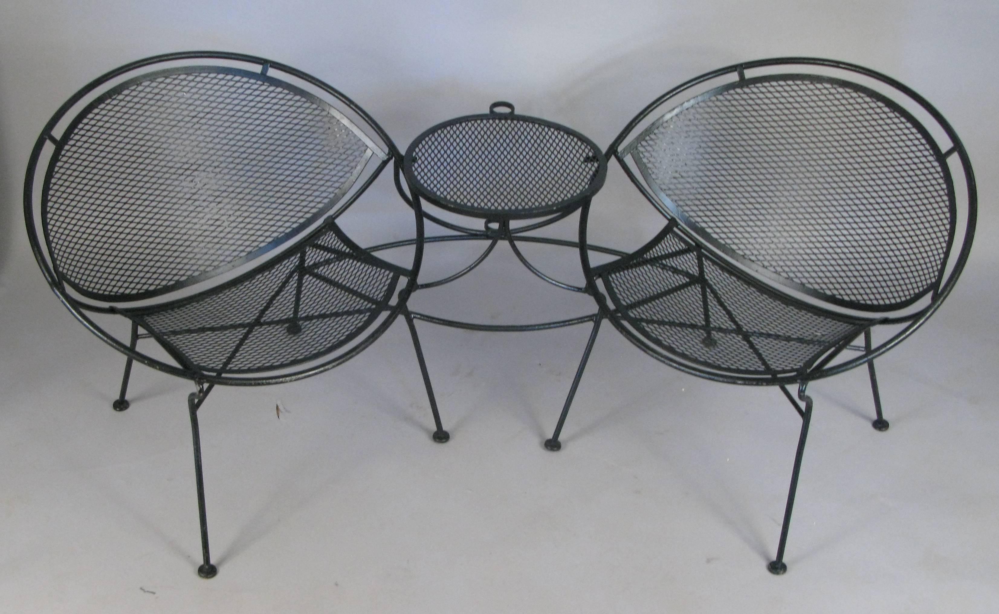 A 1950s wrought iron 'tête-à-tête' from Salterini's Radar collection, designed by Maurizio Tempestini. Very comfortable and stylish, the two lounge chairs are connected by a table between, which also incorporates an umbrella holder. The chairs are