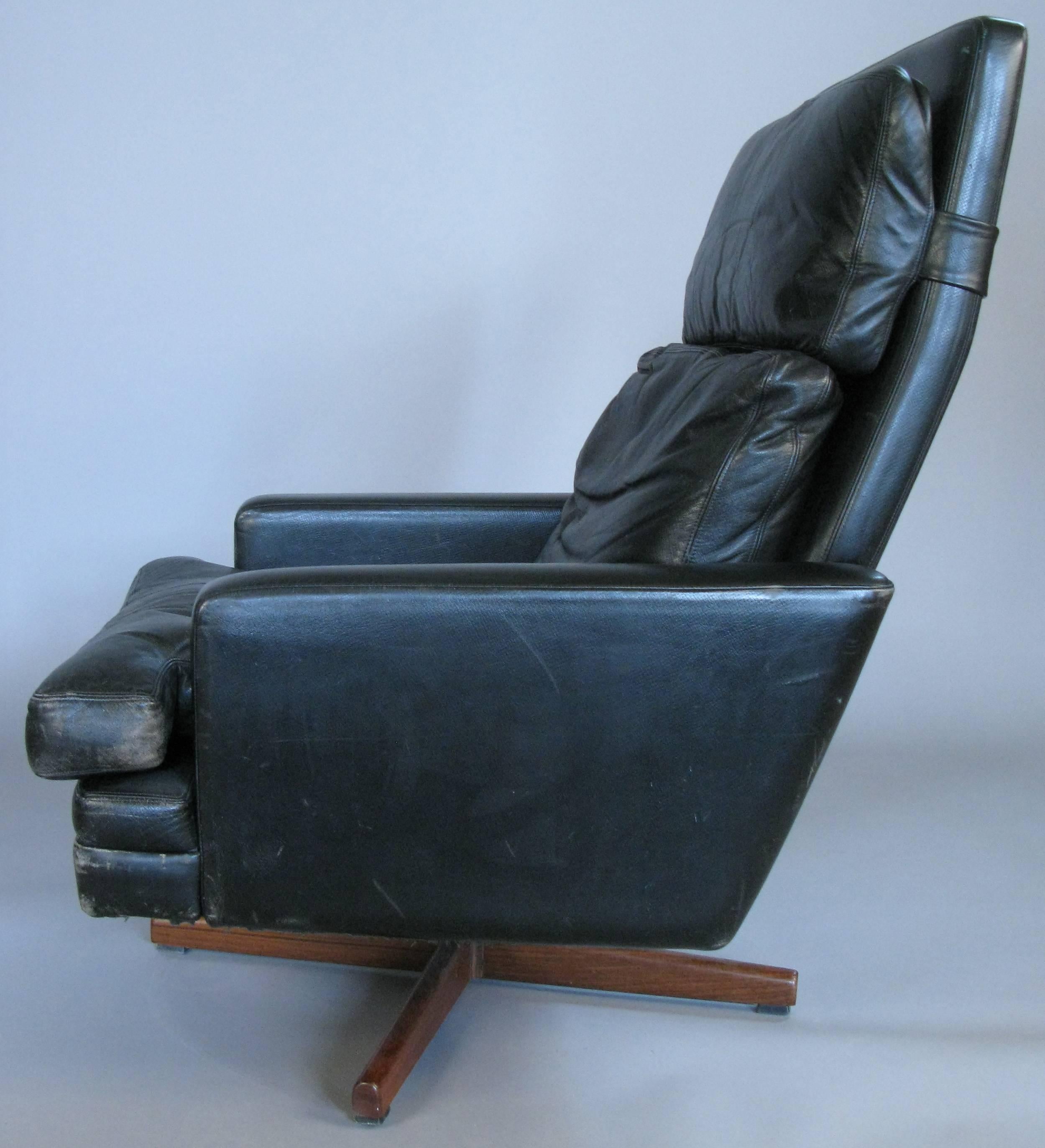 An outrageously comfortable and stylish 1960s black leather swivel and tilt lounge chair designed by Fredrik Kayser. Down filled cushions and a rosewood base. A small chrome lever allows the chair to be set a fixed tilt angle. Age expected wear