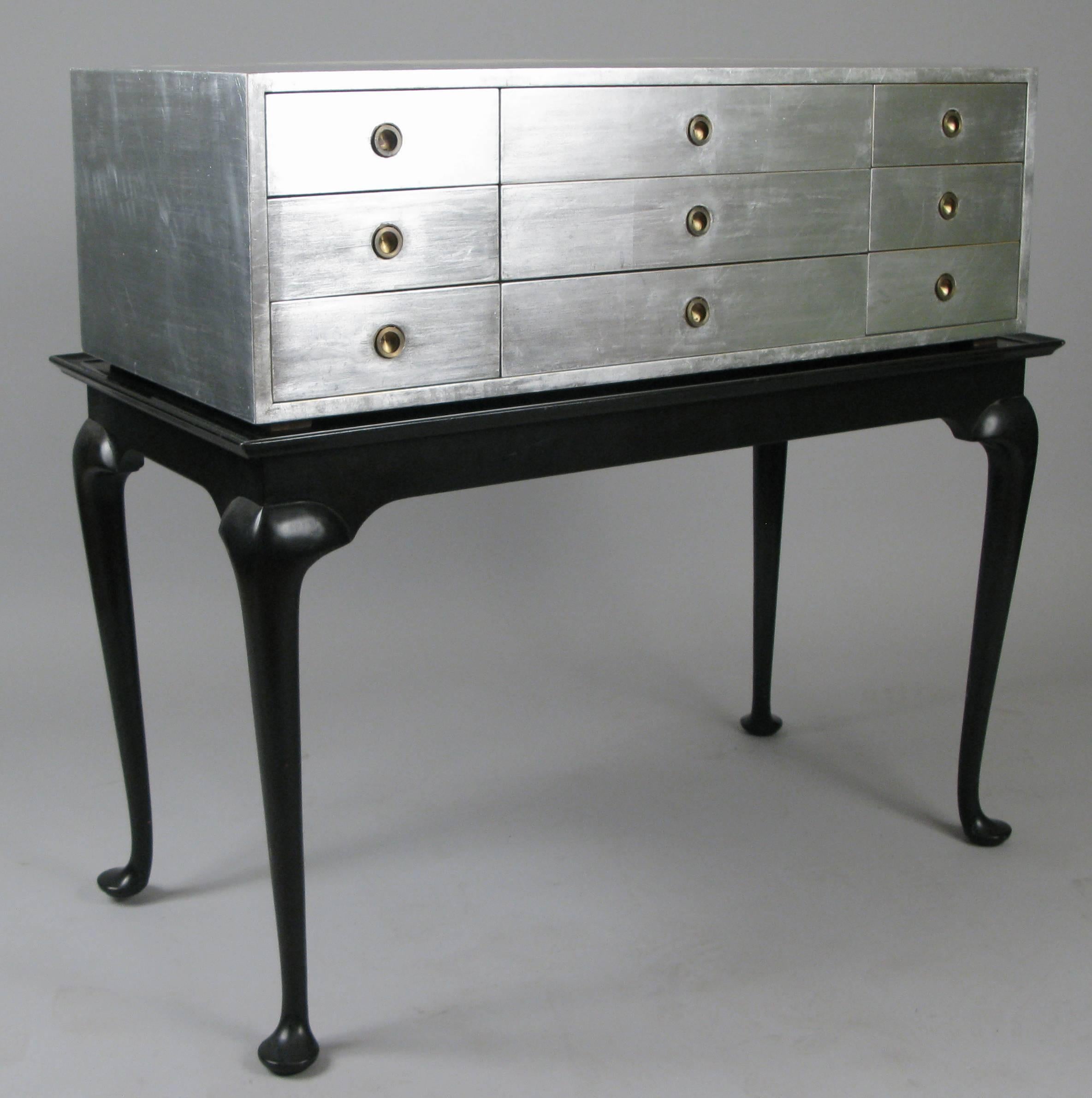 An outstanding vintage 1960s nine-drawer chest by Kittinger. The case fitted with nine drawers with recessed brass ring pulls, finished in beautiful silver leaf. The case rests upon a black lacquered base with cabriole legs. Perfect for a wide