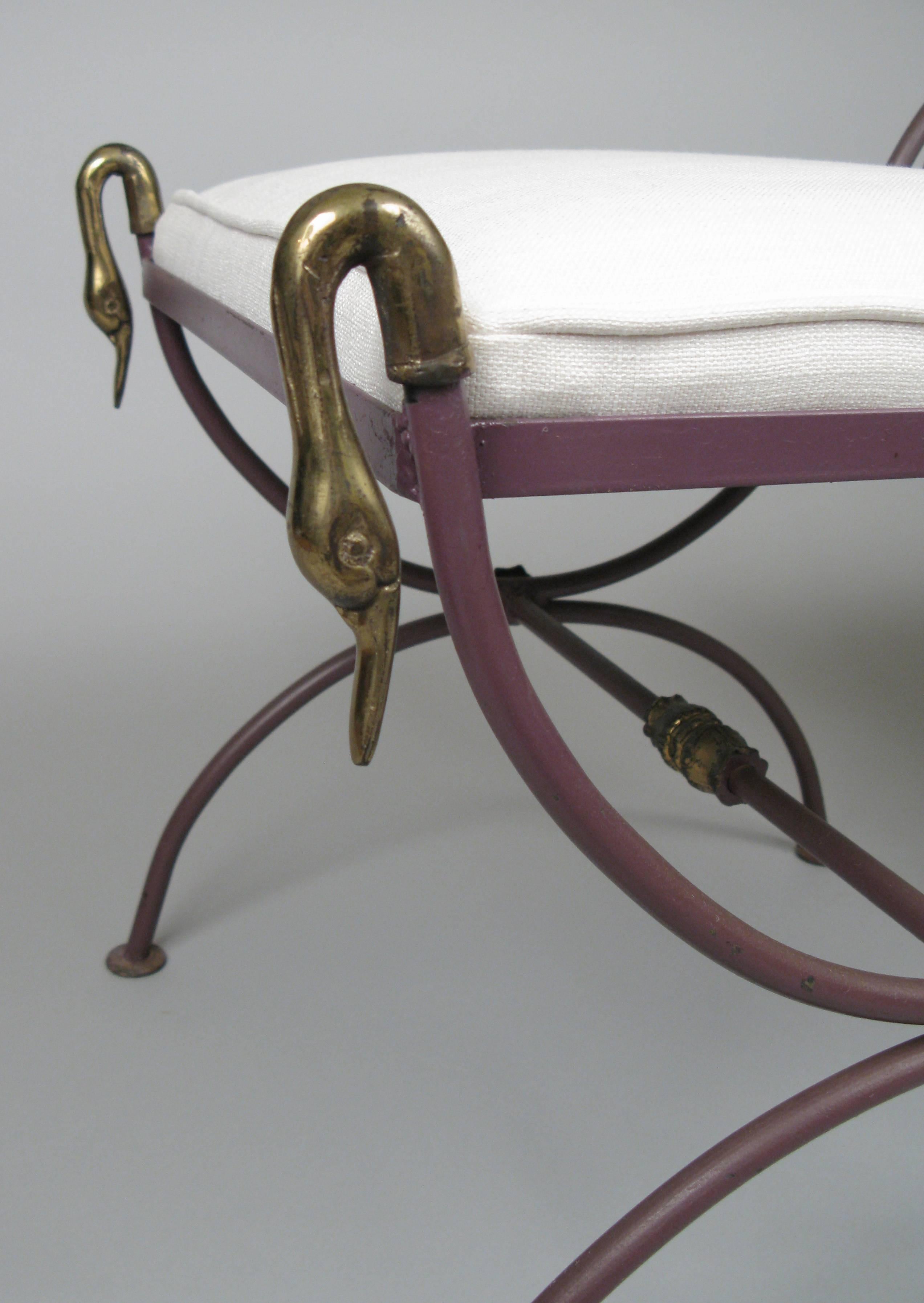 A pair of neoclassical benches in wrought iron with brass swan heads and details and curule bases. In their original dark purple finish, with seats newly upholstered in ivory linen.