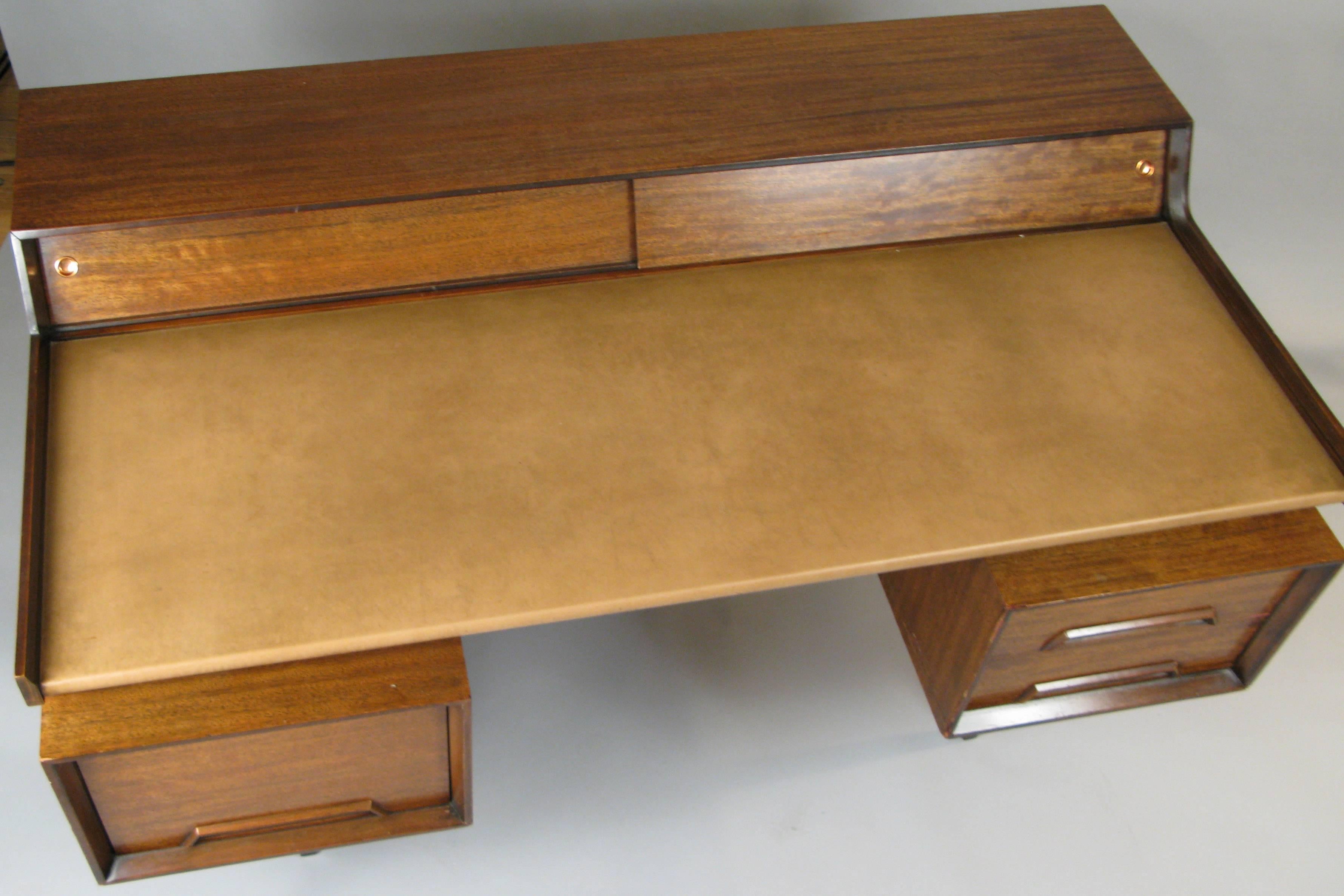 A very handsome vintage 1950s desk designed by John van Koert for Drexel. Designed with a leather writing surface floating above a pair of storage compartments, one with angled file storage. The top with a raised portion with sliding doors