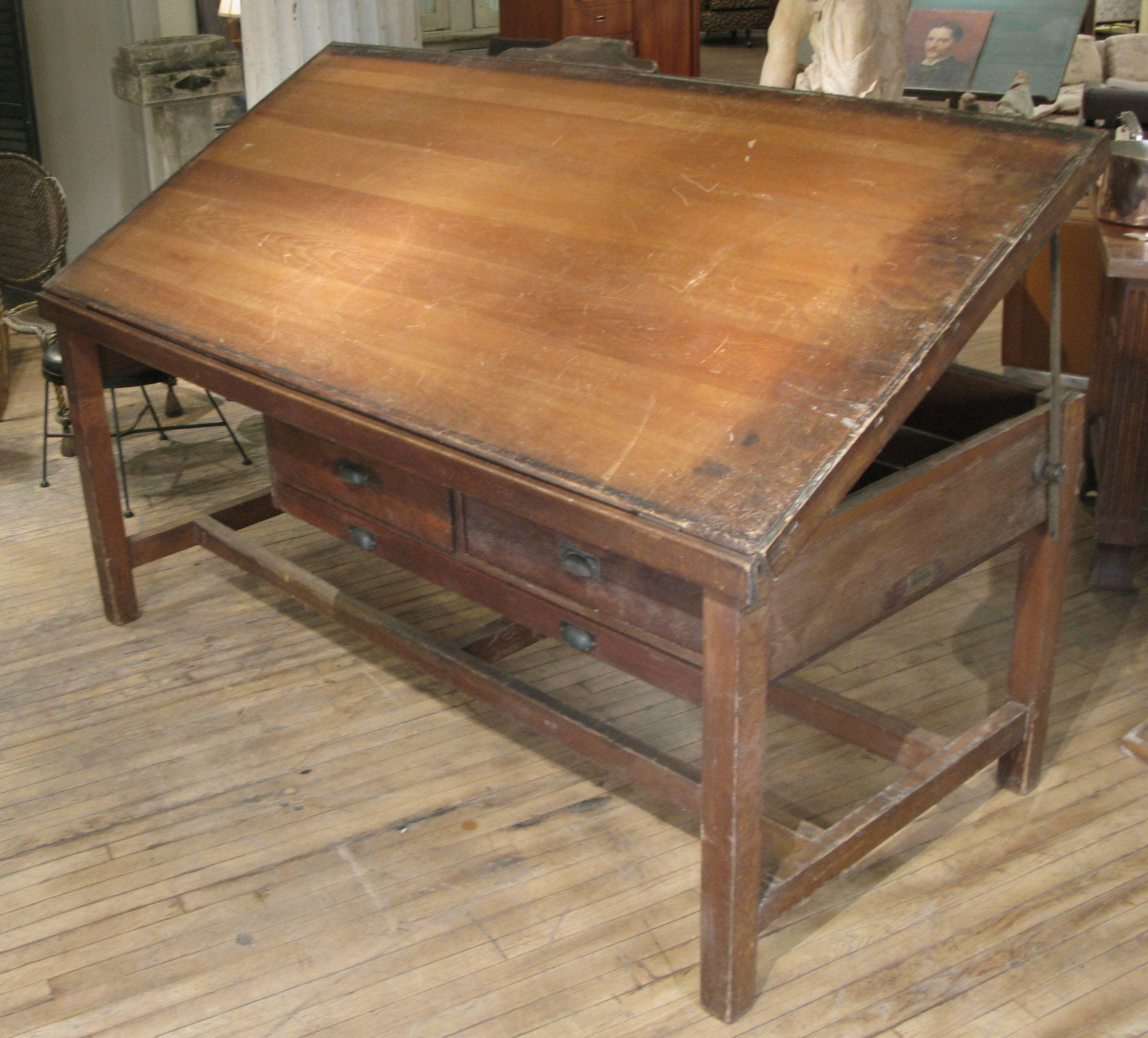 A very handsome large antique drafting desk with a tilt adjustable top, two large storage drawers and a wide drawer for drawings. Also has brackets mounted on the back for holding rolled architects plans. Also has removable block height adjusters