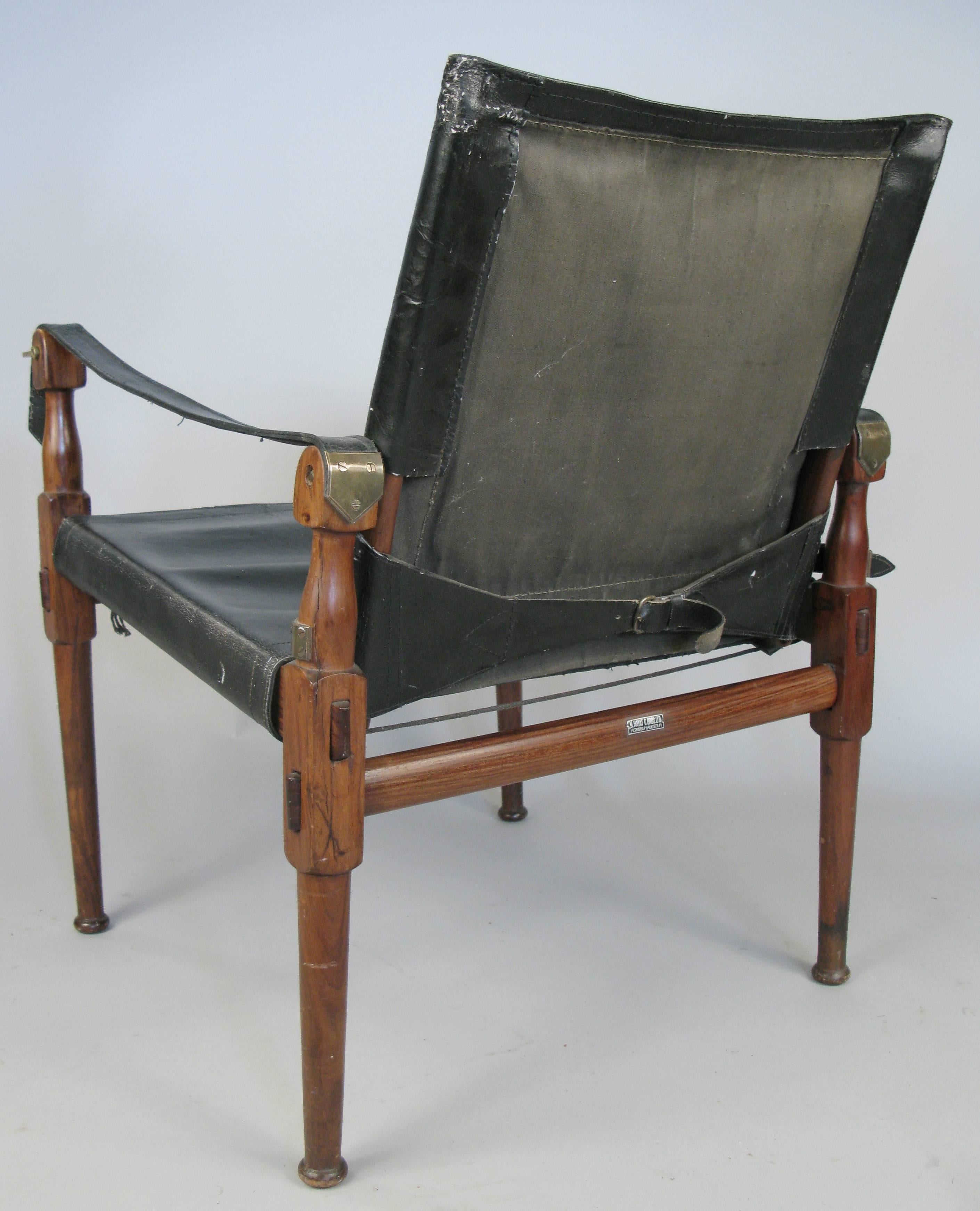 A Classic vintage mid-20th century safari Campaign chair with rosewood frame and black leather seat and back. Made in M. Hayat in Pakistan.