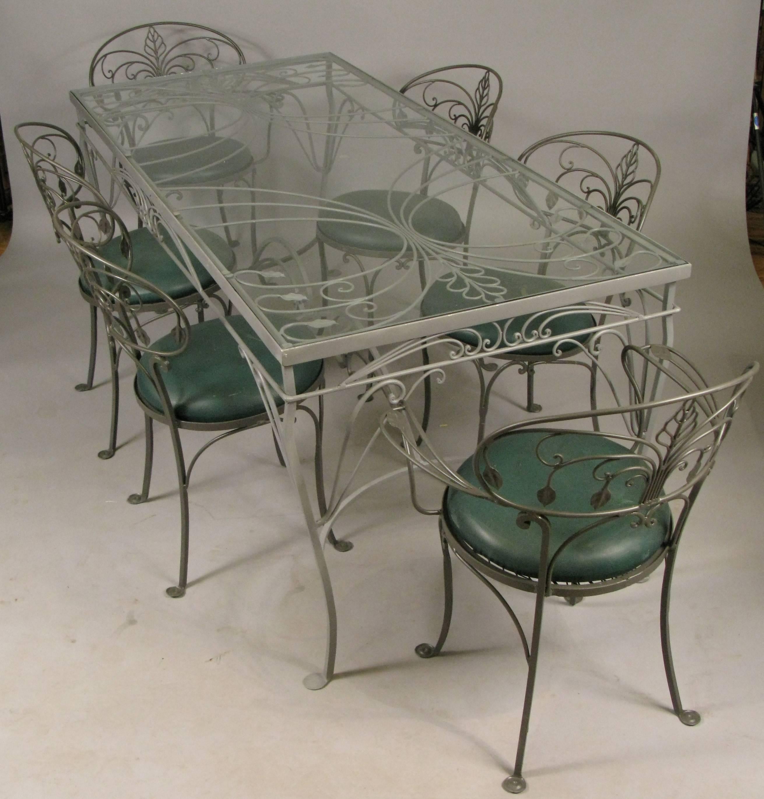 A beautiful vintage 1950s wrought iron garden dining set made by Salterini. This is one of their best tables, with beautiful scroll details, and the matching set of six chairs, including a pair of armchairs. The entire set has been refinished with a
