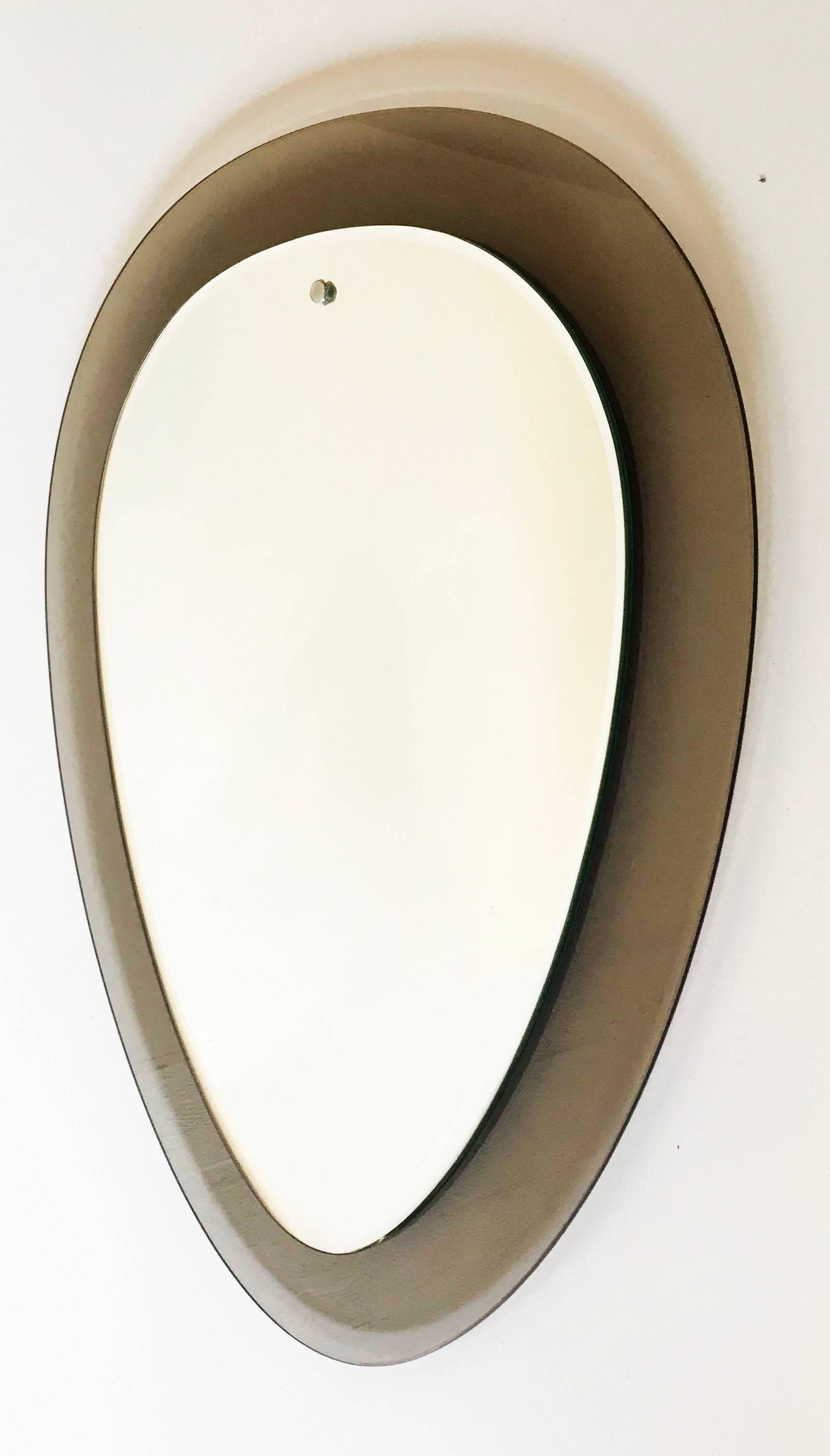 Very unusual shape for circa 1960s bevelled trapeze mirror by Veca, smoked glass frame, nickel-plated brass screw heads. Italy mirror measures: 18 inches W, 24 inches H.