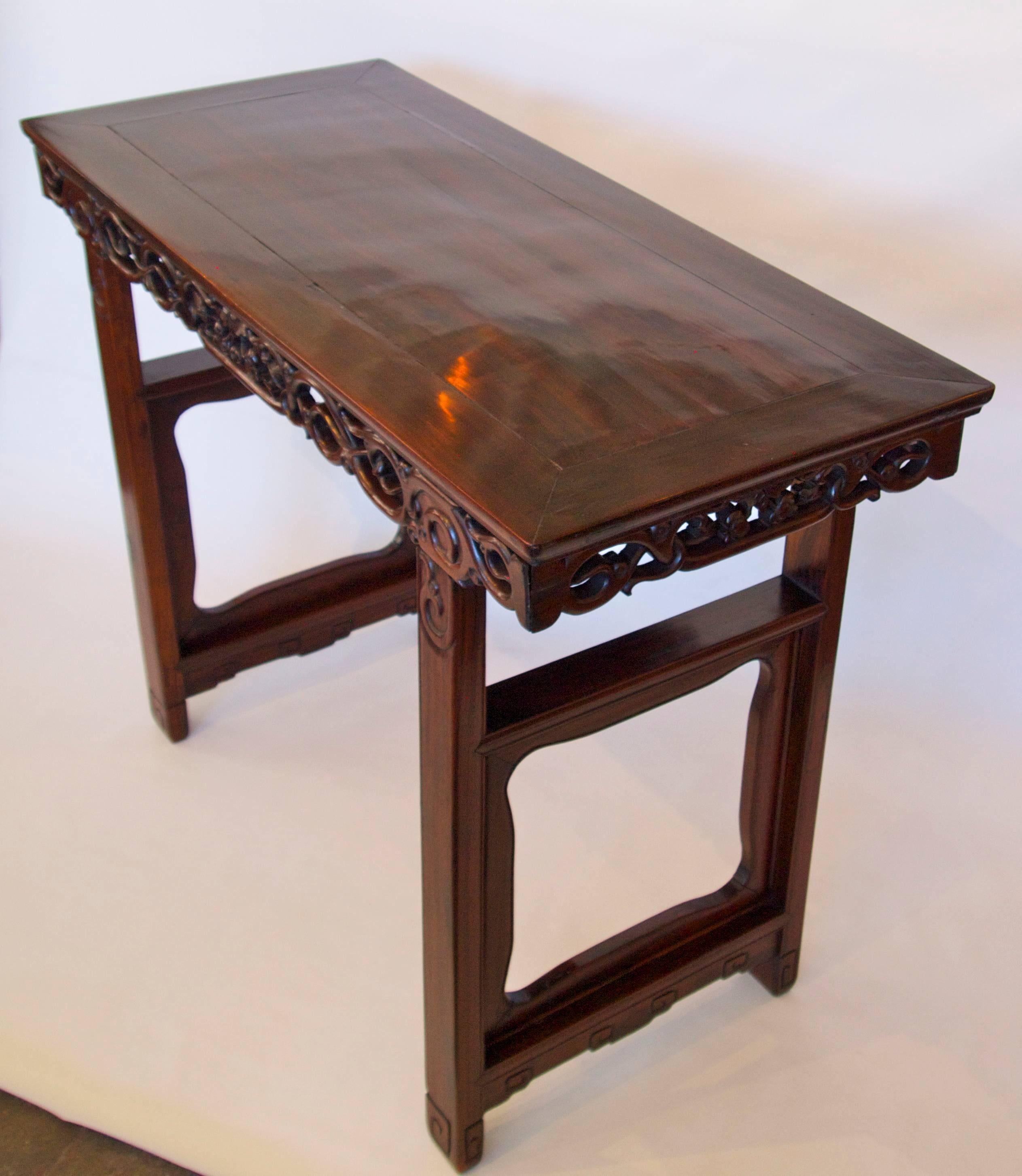 Beautiful late 19th century Chinese hongmu wood tall altar table; rectangular top fits on an elaborately carved and pierced frieze and supported by carved and shaped open end panel legs with carved scroll feet. Excellent color and patina.