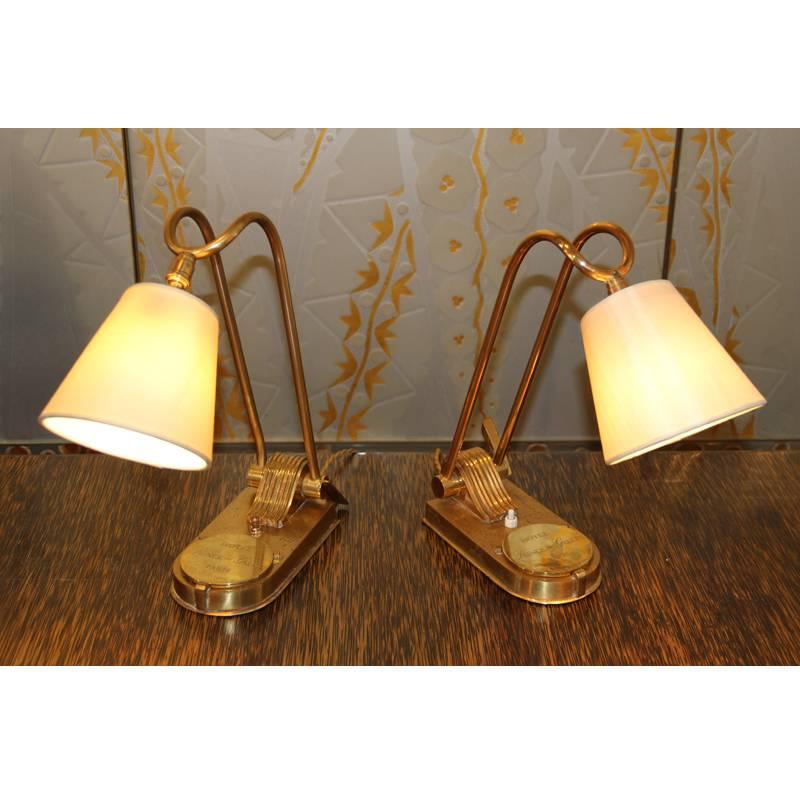 This pair of lamps is from a collection of 26 from the Prince de Galles hotel in Paris, France. The lever on the side lifts up to adjust the angle of the lamp. At the base of the lamp is a bronze plaque monogrammed with the hotel's name, which