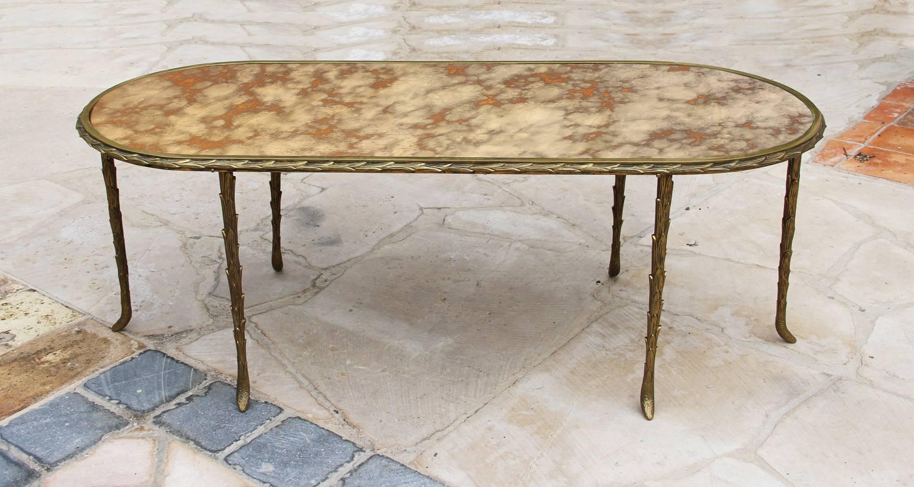 This elegant Baguès coffee table is in its original condition, it has a gilt bronze, palm trunk motif frame and a mirrored top. The feet on each leg have a ram Horn shape. The bronze has a beautiful natural patina and the top is with an amazing