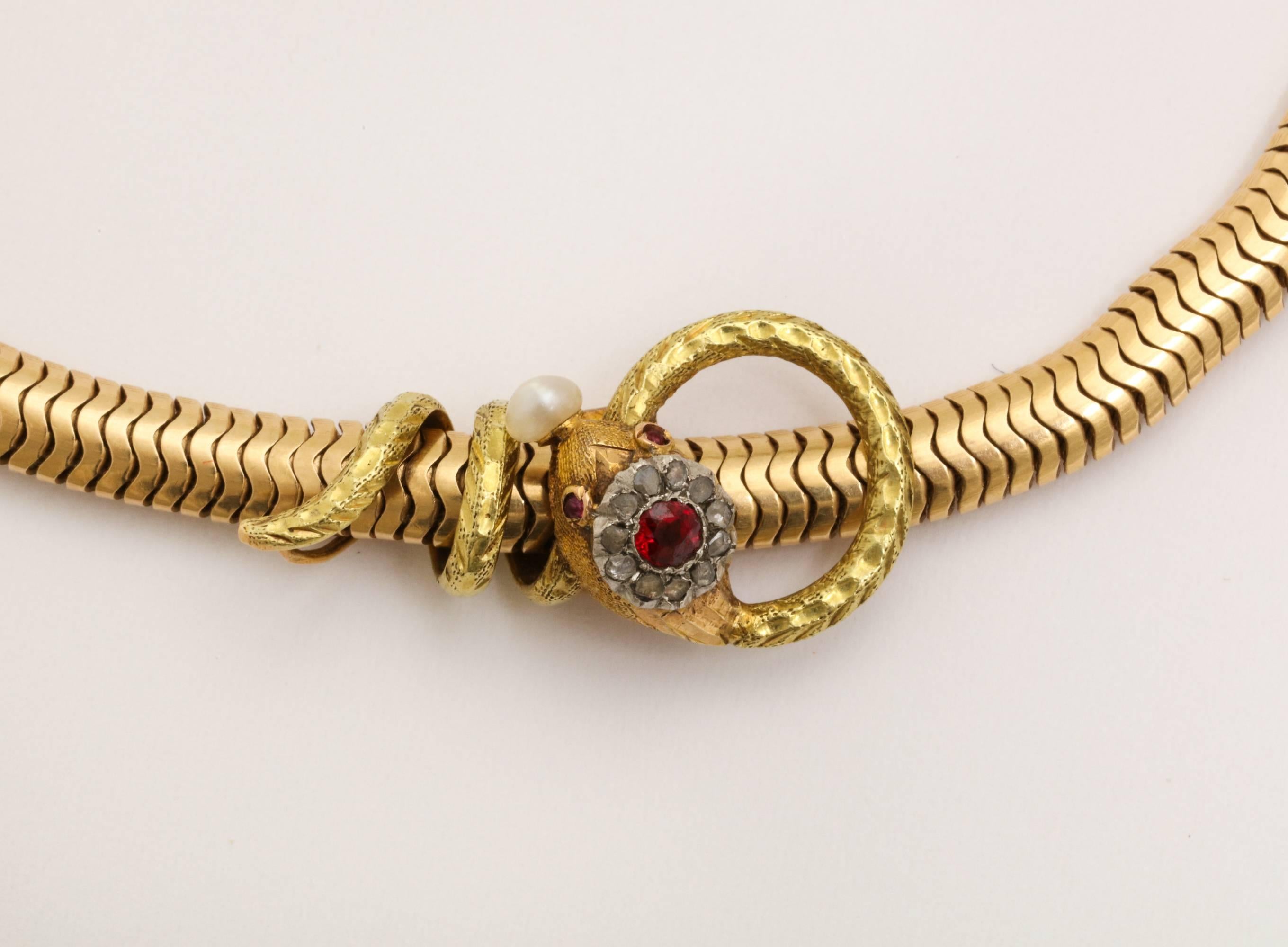 A great example of an Art Deco 18-karat gold snake coiled around a woven 14-karat gold chain. The snake is decorated with a ruby crest and surrounded by mine diamonds with ruby eyes and pearl.