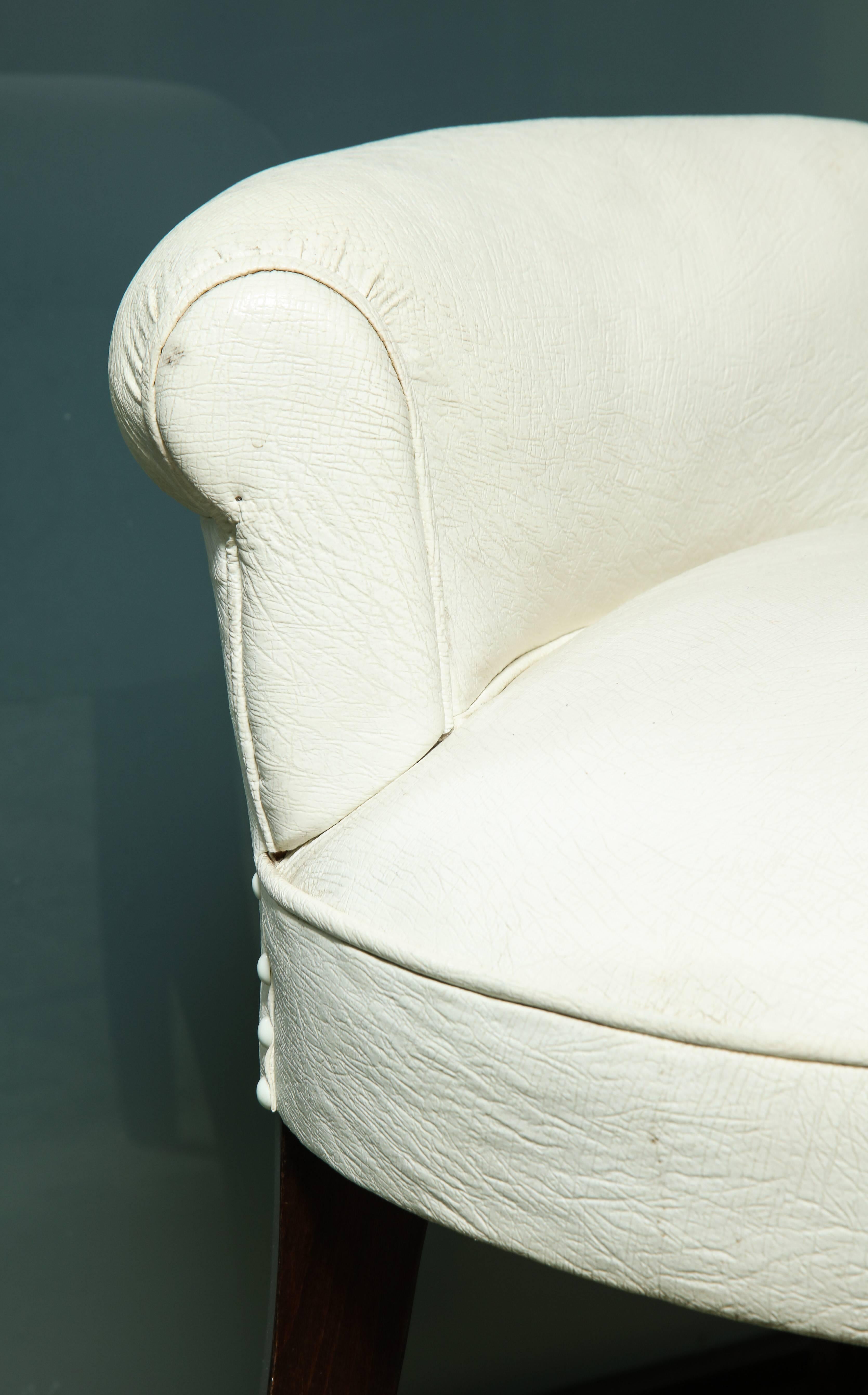A wonderful Art Deco white leather vanity stool with short scrolled back and ebonized legs.
