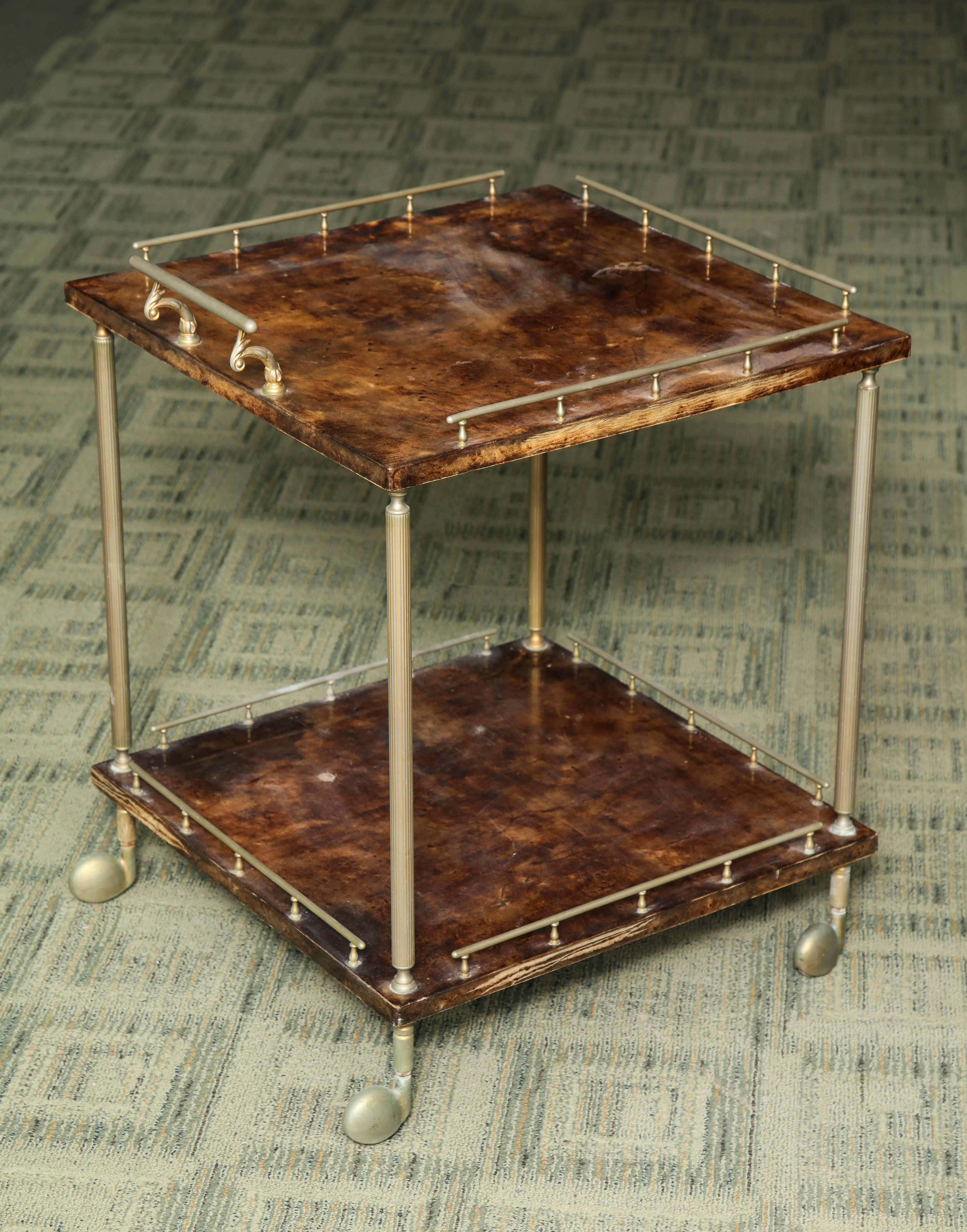 A great bar cart lacquered goatskin with metal on rolling wheels. The square art piece is petit enough to place unobtrusively but functional.