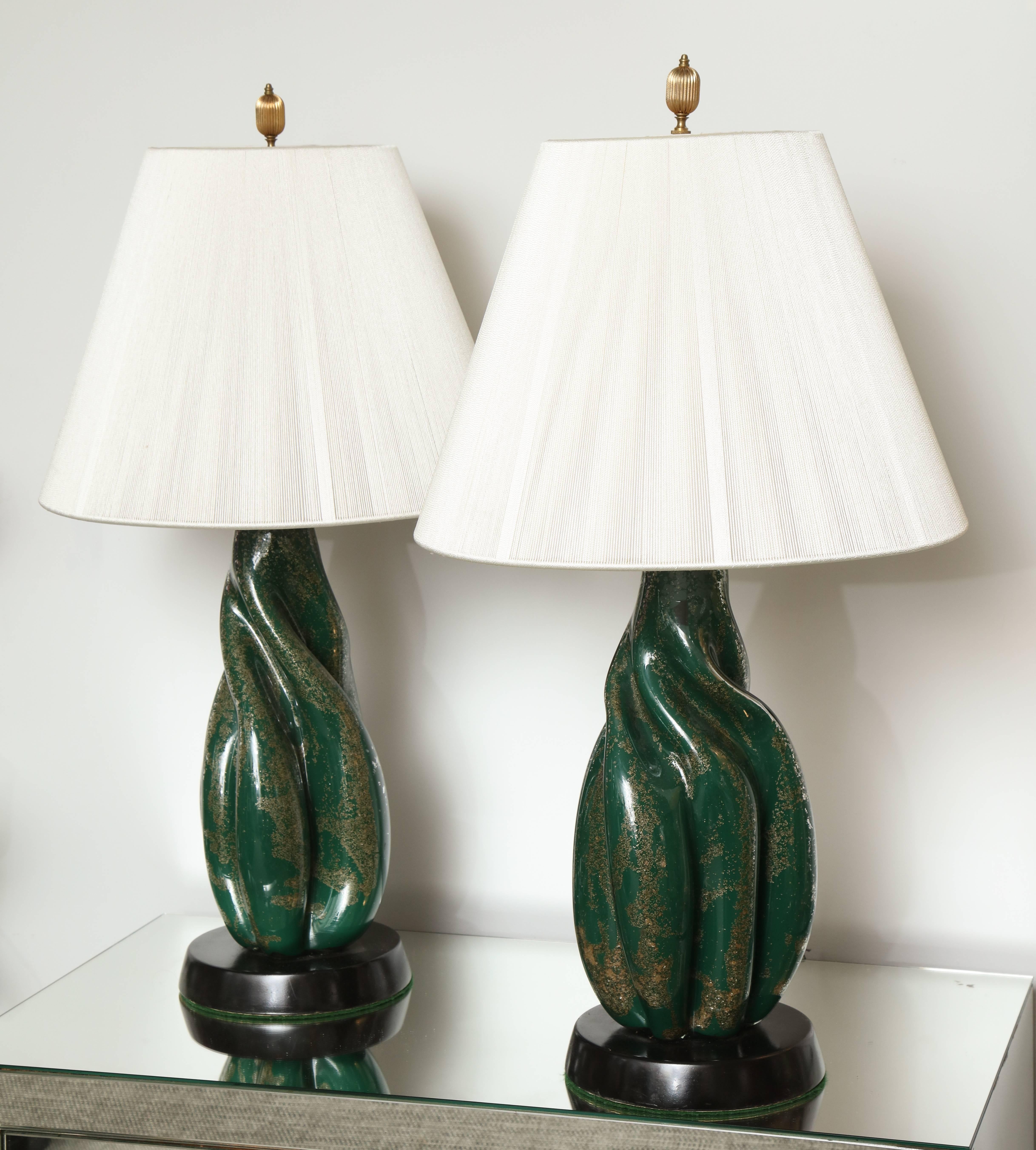 A wonderful pair of Murano lamps in green and silver/gold flecks cased in glass with a twist on a black base.