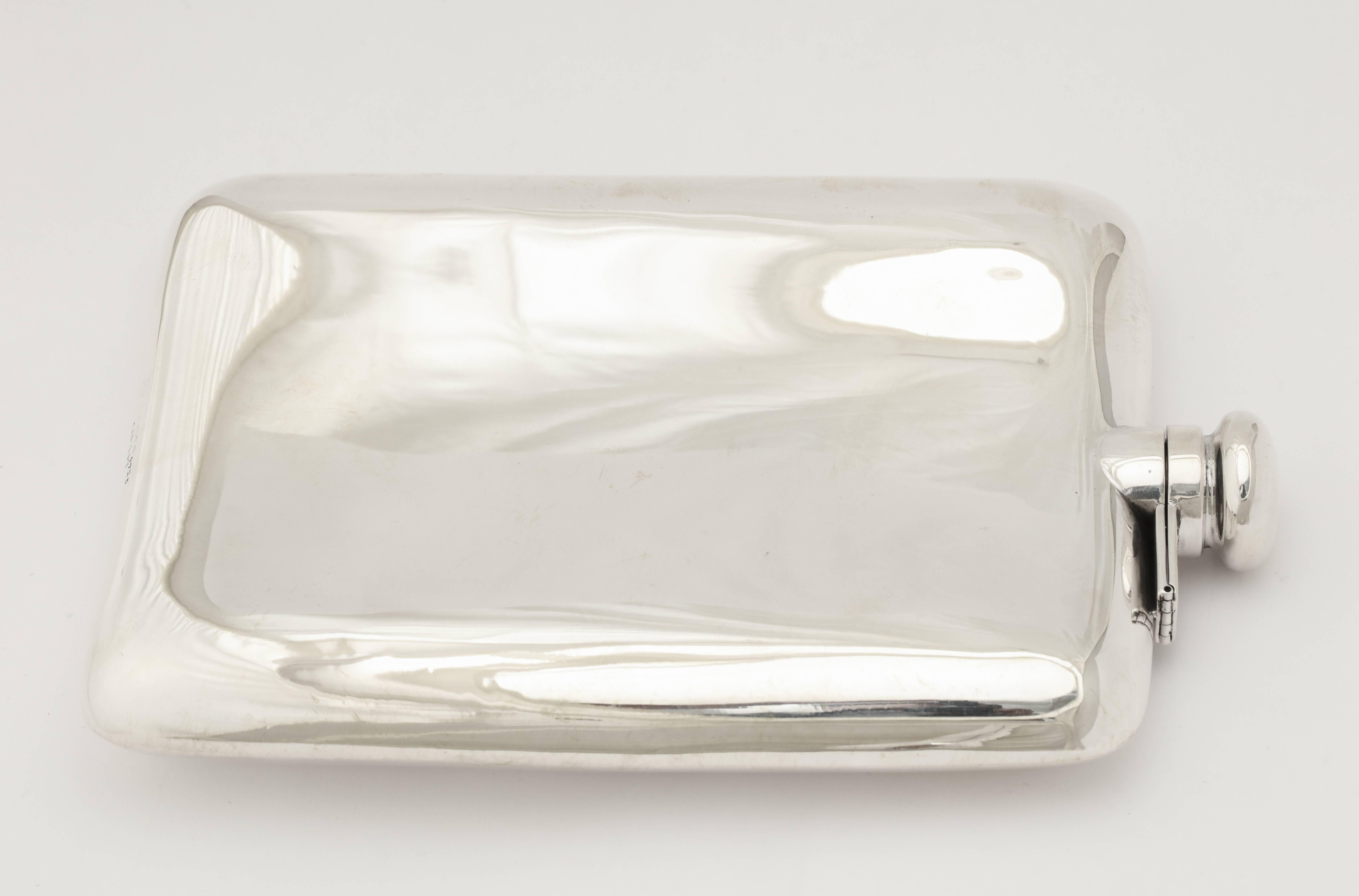 A wonderful hip flask in sterling silver with flip-top marked Cartier and with silver marks.