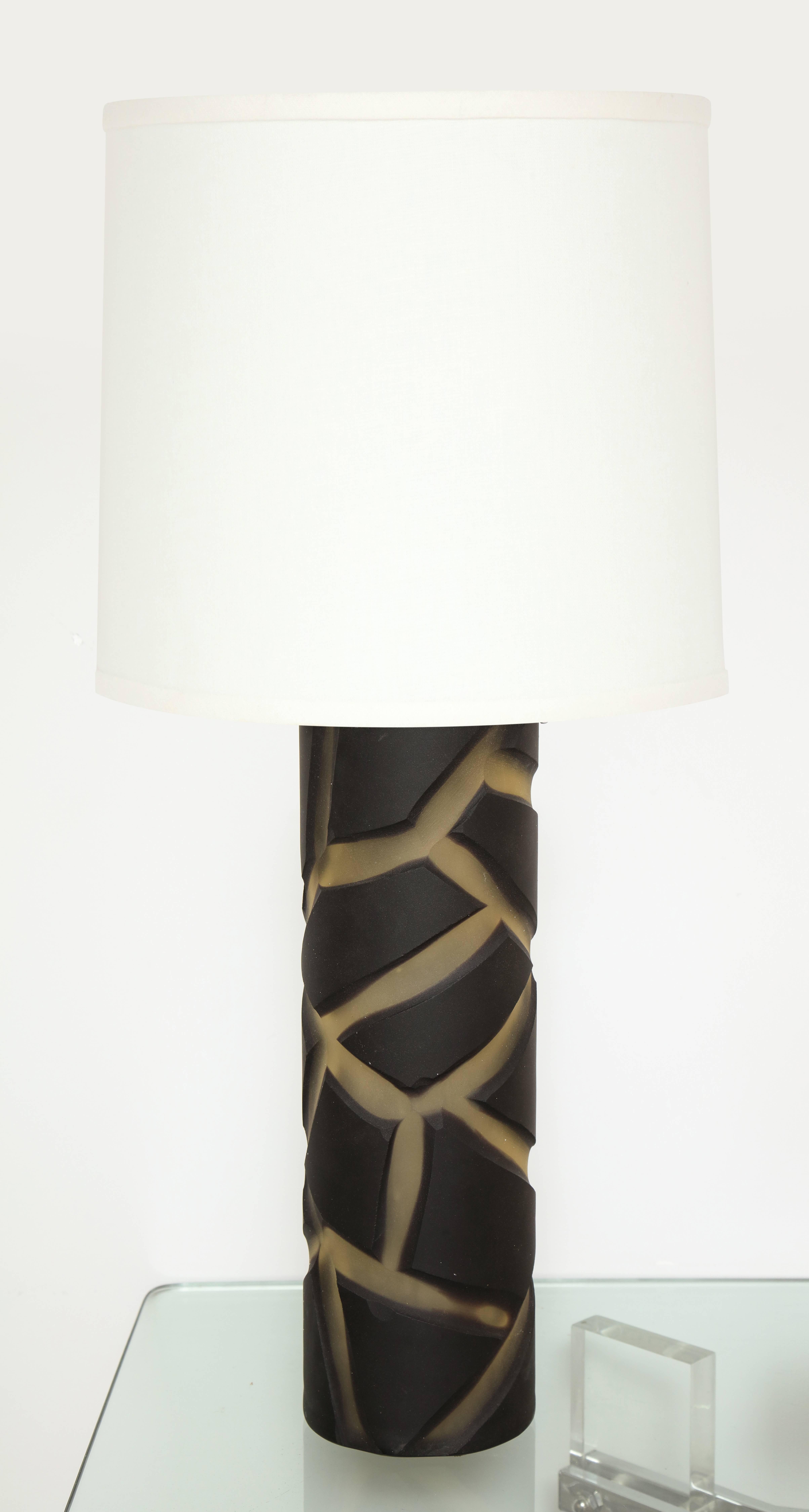 A elegant pair of frosted black and white glass table lamps with a deep cut abstract geometric design in Murano glass by Vivarini signed on the base.
