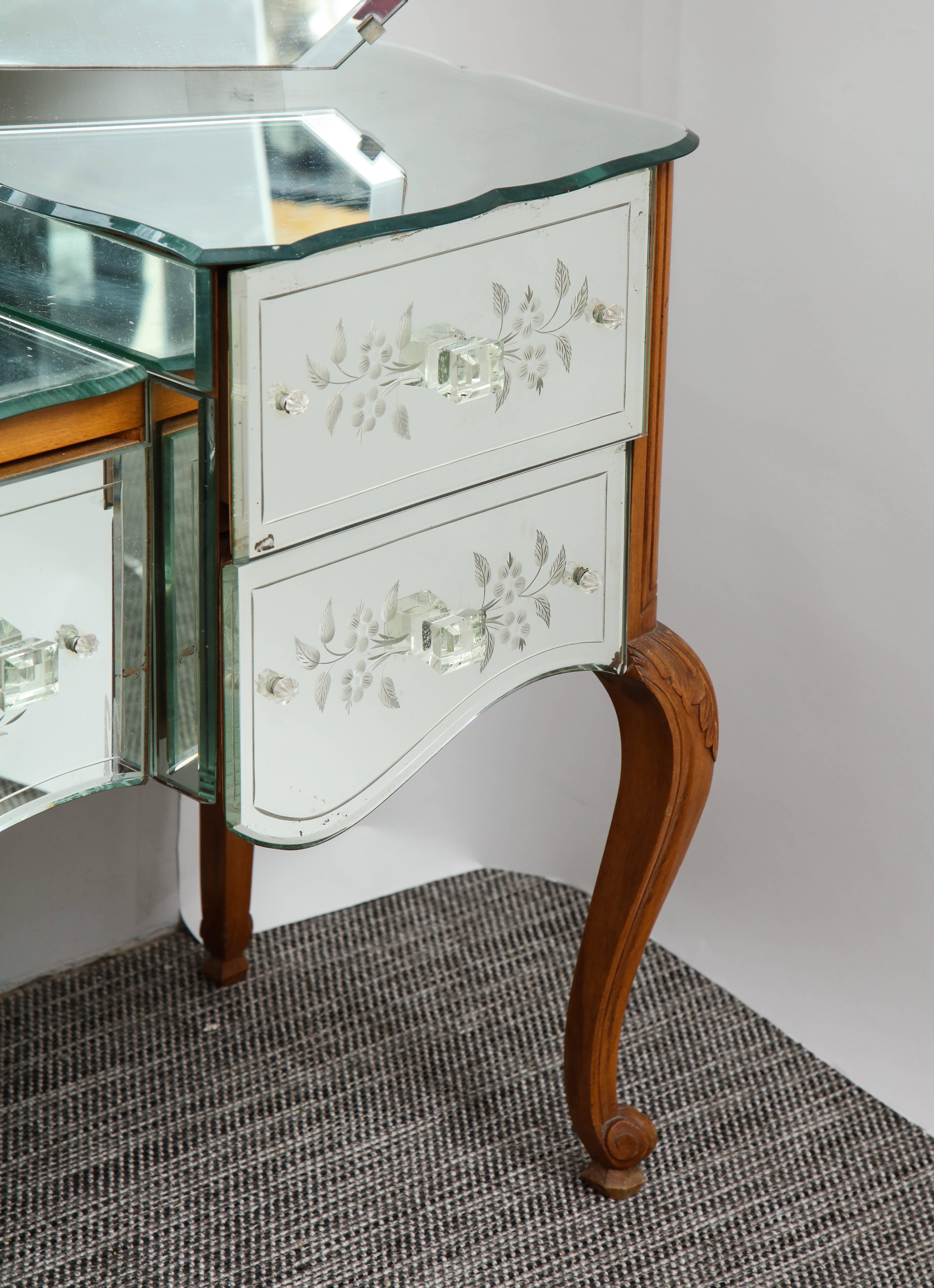 A wonderful French deco vanity with a bevelled trifold mirror on a four drawer body with floral etchings on acanthus carved cabriole legs.