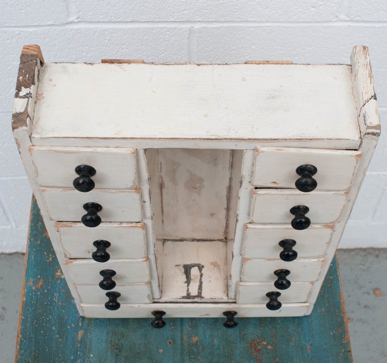 A nice run of 11 lap-jointed spice drawers in old distressed white paint on top of the original mustard. Two runs of five drawers with original tin knobs are separated by an oil or vinegar shelf.