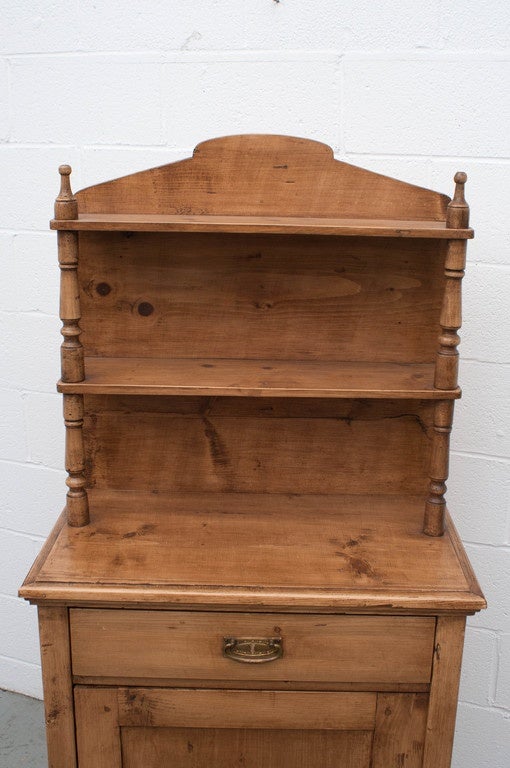 A small pine two shelf chiffonier with one panelled door and one lap-jointed drawer and a single shelf to the interior.  Finished in rugger brown wax.