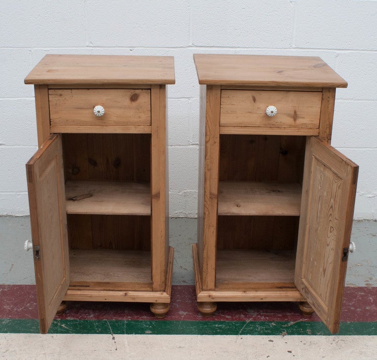A charming pair of polished pine night stands with one door and one drawer.  Single shelf to the interior.  Replaced ceramic knobs.