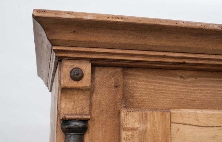 A very attractive pine armoire with two scalloped panels to each wide swinging door, flanked by ebony-stained walnut split balusters above a single hand cut dovetailed drawer.