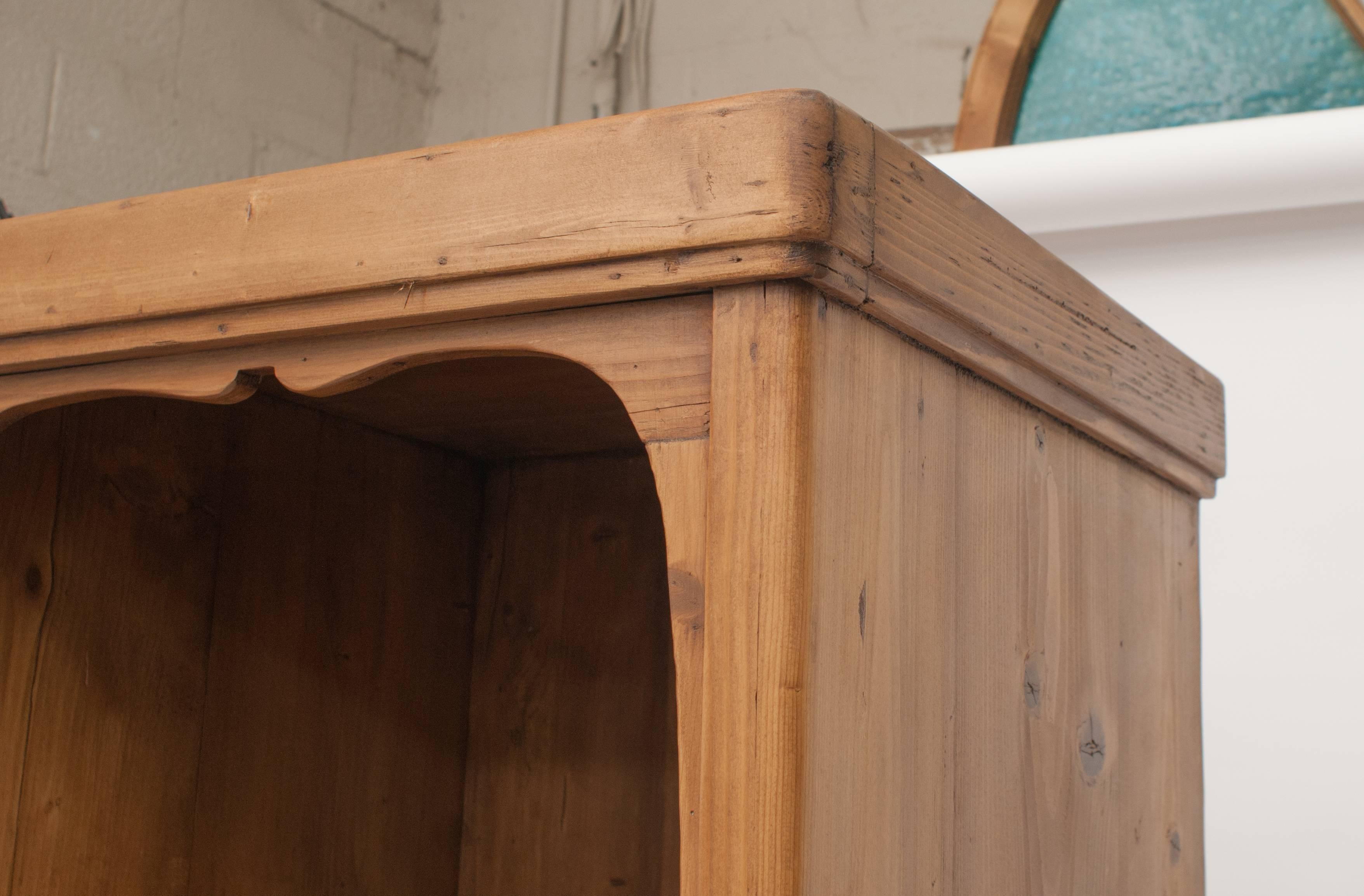 A fairly plain art nouveau period pine chimney cupboard with a single flat panelled  door beneath an open hat shelf with decorative trim and standing on bracket feet.  In excellent condition with a beautiful rich colour, this piece has a hanging
