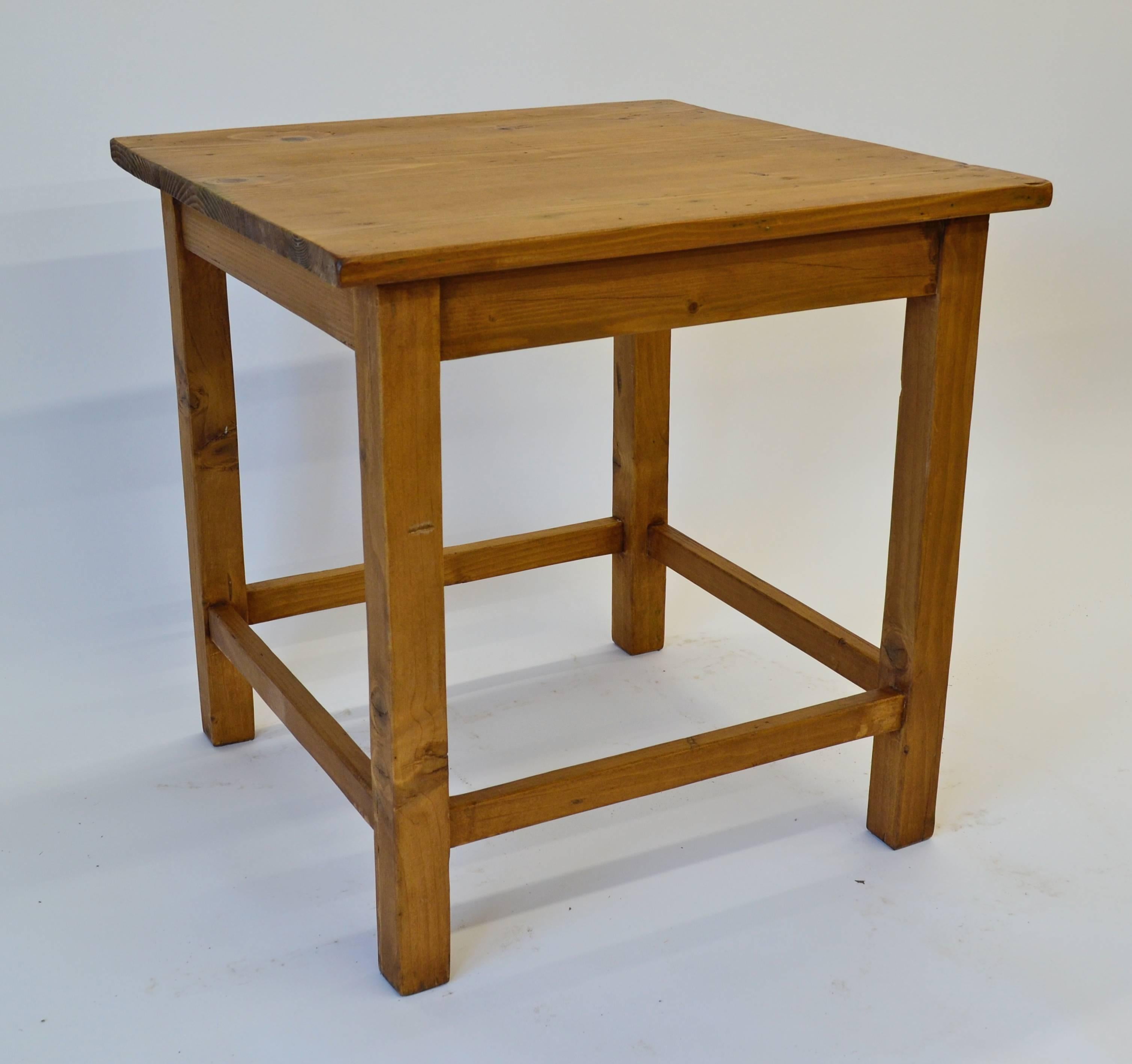 A rustic pine stretcher-base end table on straight legs and with approximately cubed dimensions Very attractive natural distress all-over and great warm color.