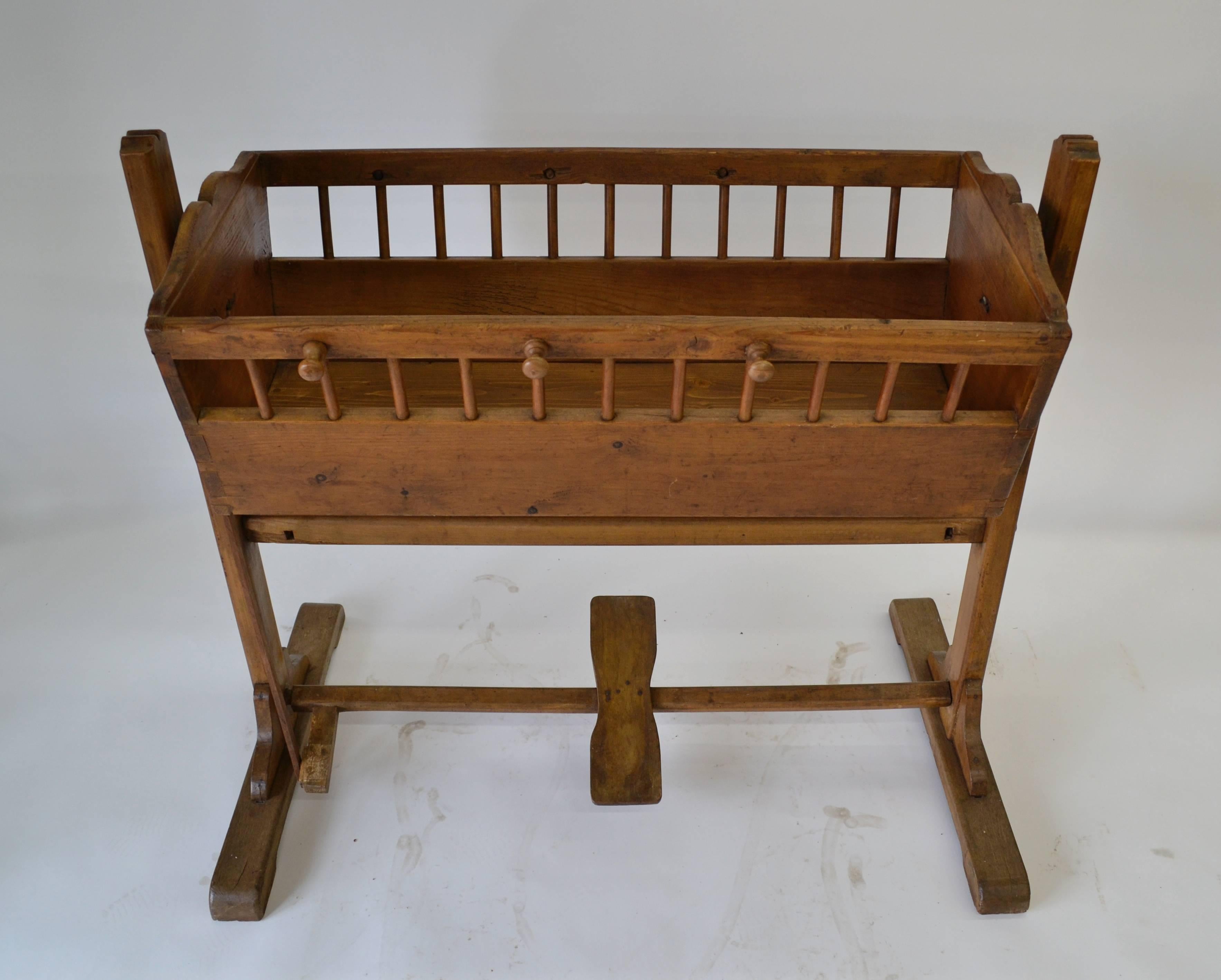 An outstanding pine cradle on a trestle base of oak and beechwood, in almost entirely original condition. Operating the treadle gives a gentle swinging motion to the cradle; when stationary a wooden peg holds the cradle still. Five of the six turned