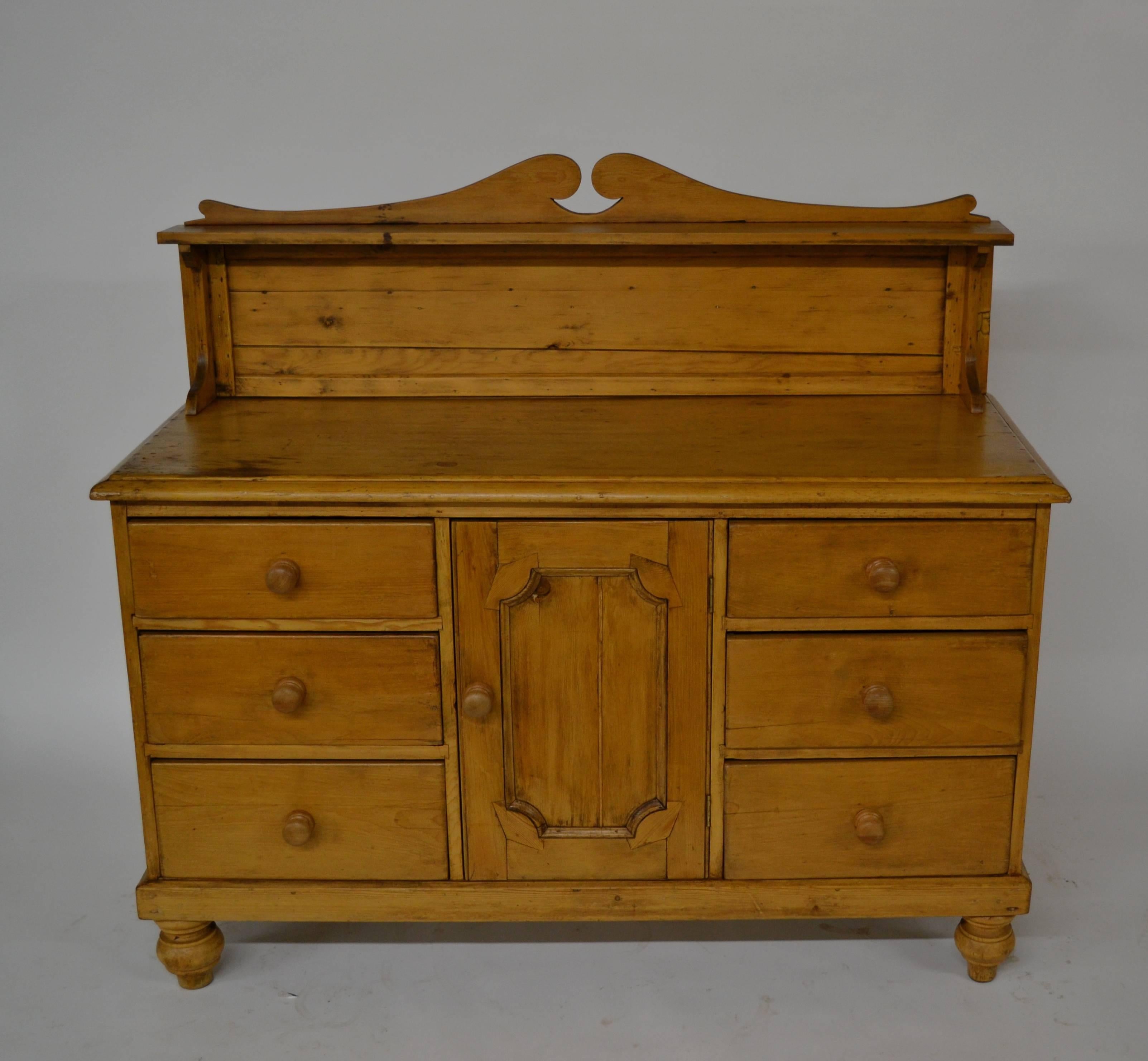 A Classic Northern English sideboard from Yorkshire, (downstairs Downton Abbey?), with a graceful broken pediment to the shelved splashback. Two rows of three drawers with delicately hand-cut dovetails flank a central cupboard door. The curved