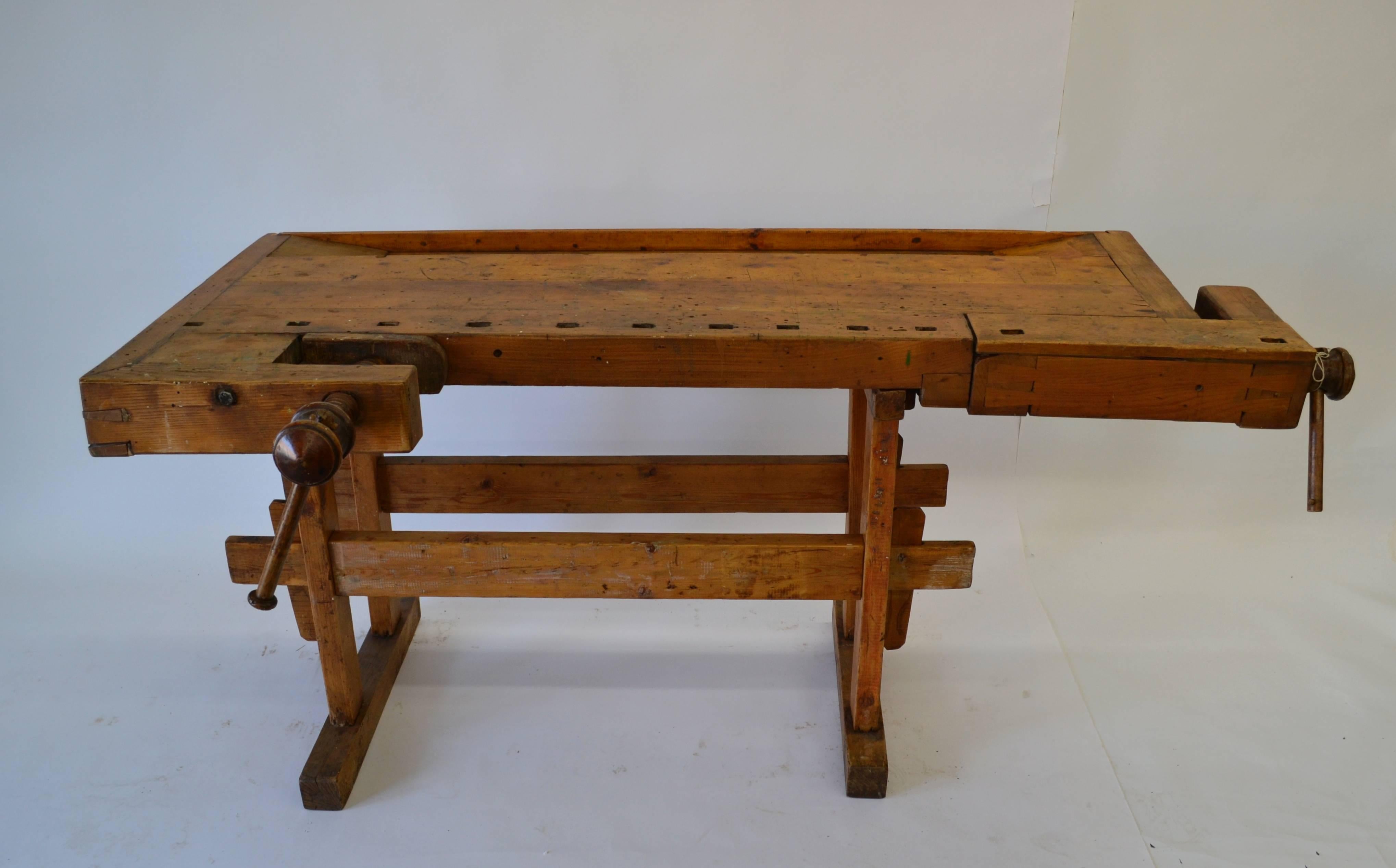 Another outstanding workbench from our European sources. The three to four inch thick oak top has wooden screw turned vises on the front and left hand side, both showing bold exposed dovetail construction. The collapsible pine and oak base has two