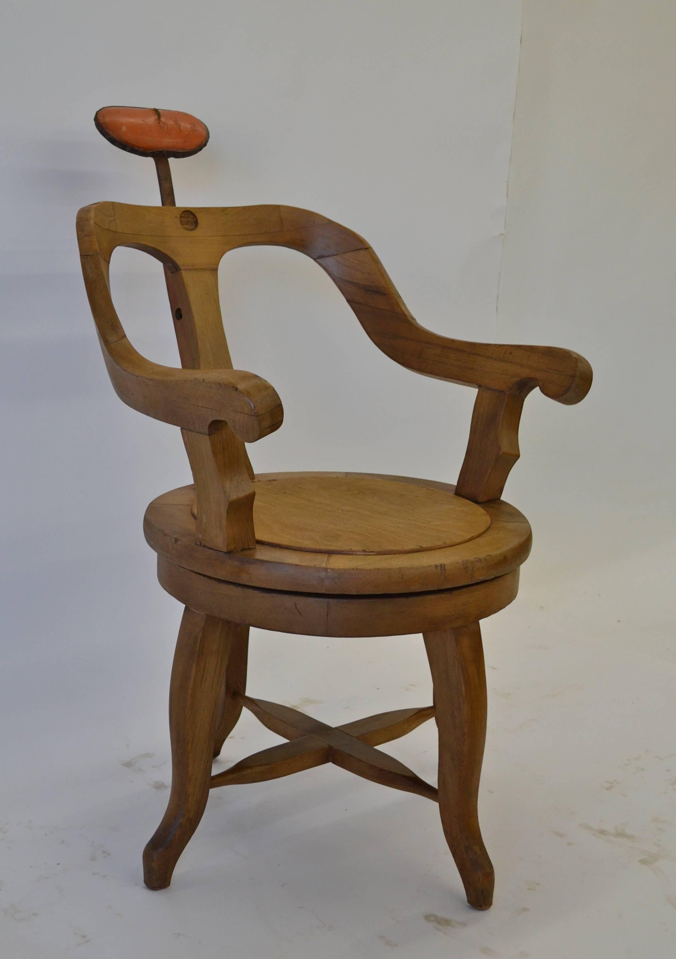 A handsome vintage curvilinear barber’s chair from mixed hardwoods. The comfortable back and continuous arms are attached to an upper seat which revolves 360 degrees on “Lazy Susan” cast wheels mounted between it and the base. Four graceful cabriole