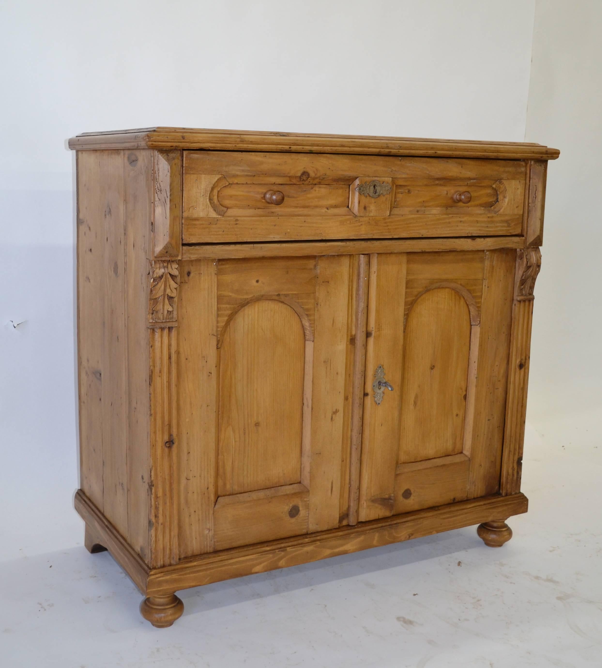 A small pine dresser base with great character and wonderful rich color. A single hand-cut dovetailed faux paneled drawer with zinc escutcheon plate sits above two arch paneled doors. These are flanked on the front sides with applied fluting and