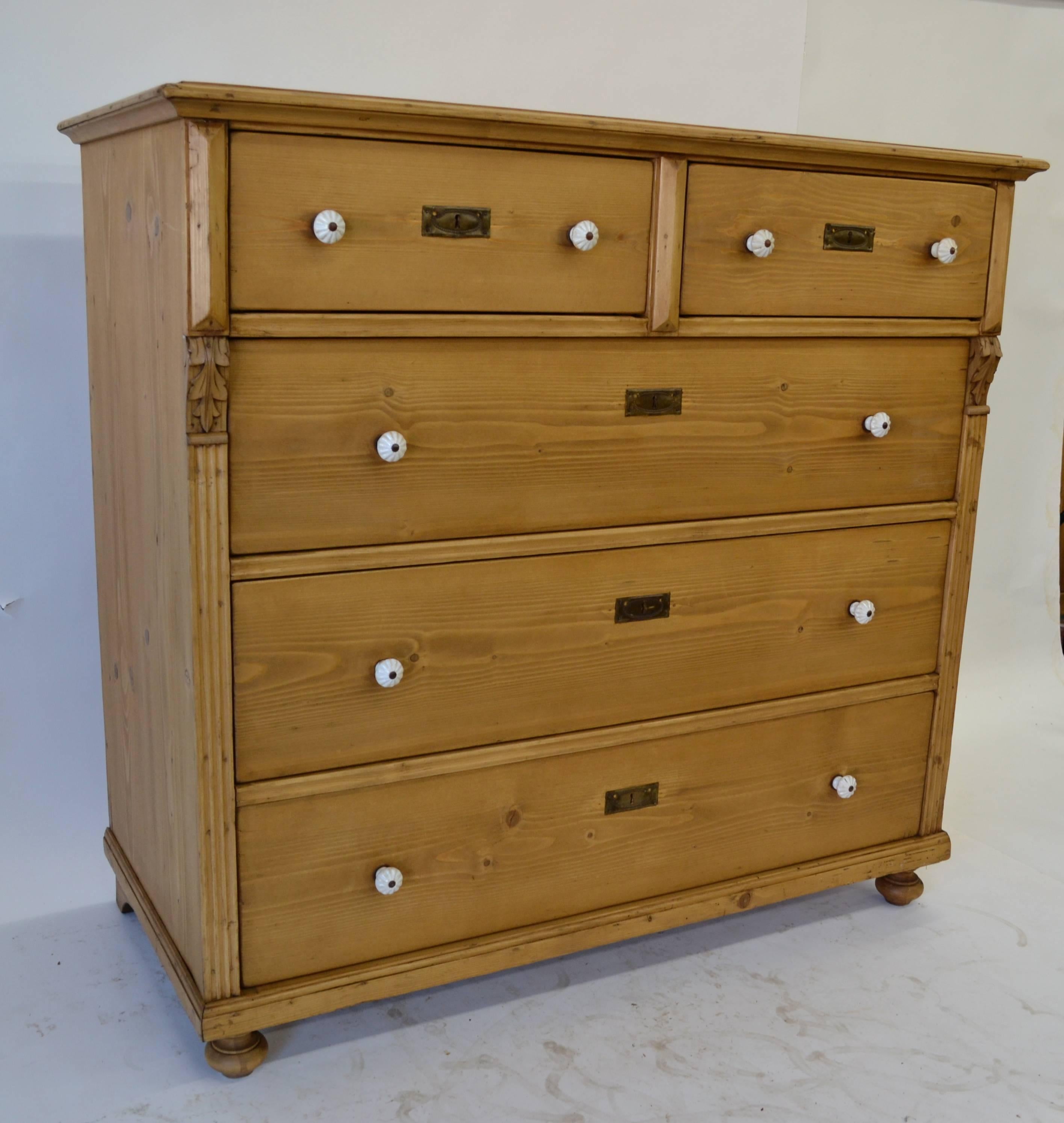 This is a beautiful large chest of five hand-cut dovetailed drawers. Two deep short drawers sit above three long, bordered at the sides with fluting and hand-carved acanthus leaf corbels. Lovely blonde patina with original ceramic knobs.

