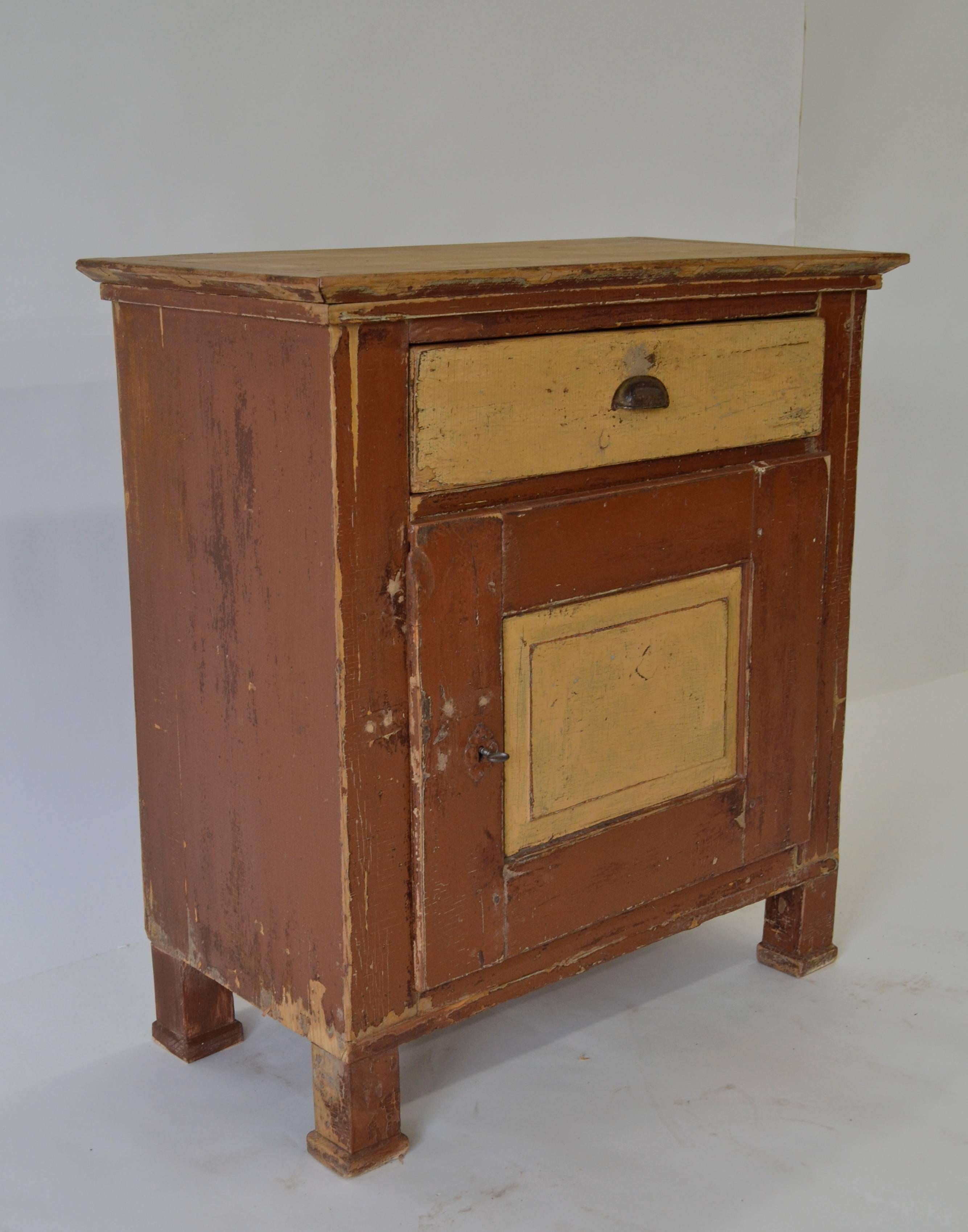 A simple country one-door pine base with great character and superb construction in a classic central European form. Straight rails and stiles enclose a single hand-cut dovetailed drawer with a bin pull handle and a single overlay door with a raised
