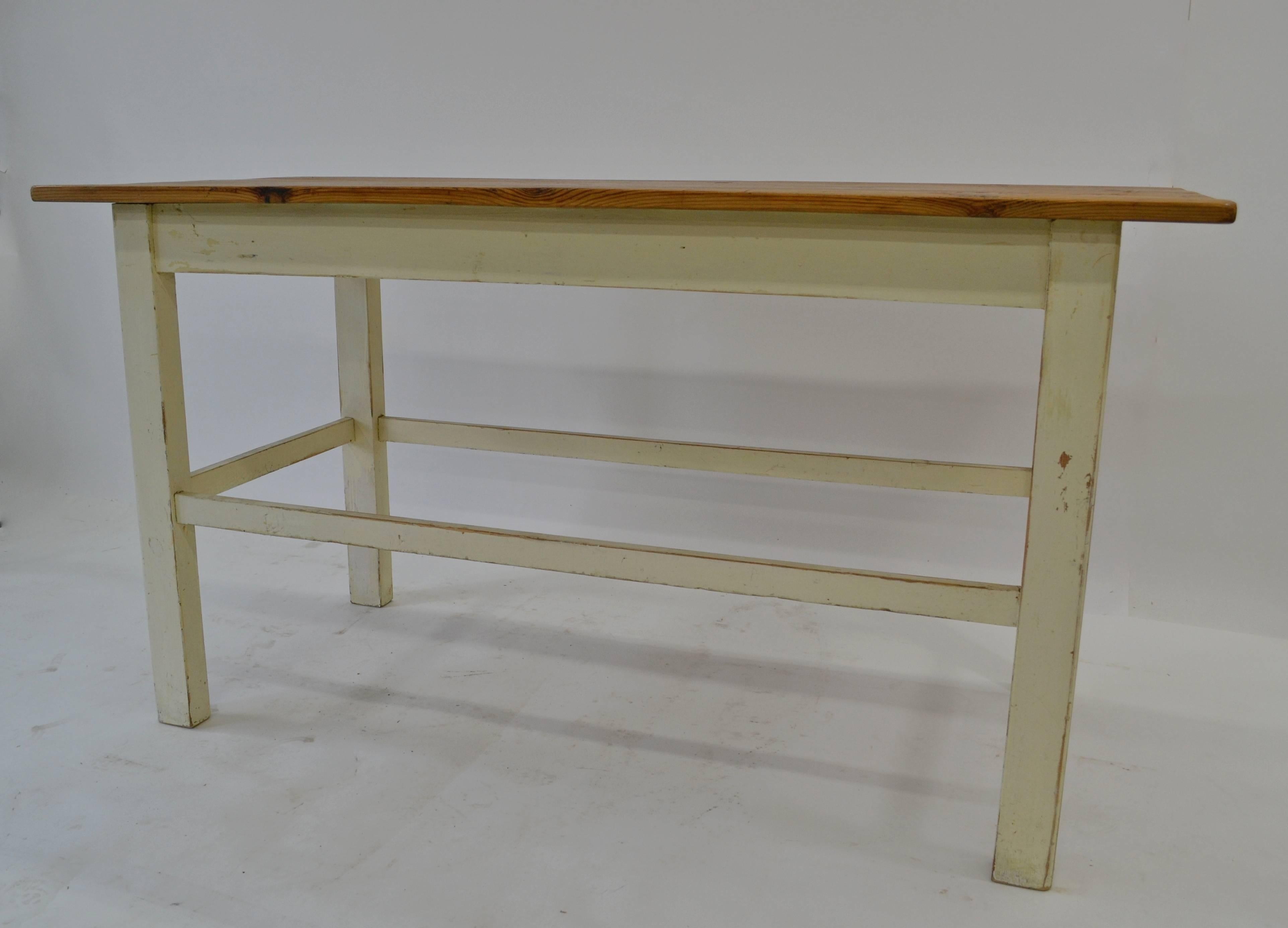 This is a simple but very attractive pine work table, great for a studio or retail setting. The polished pine top has a lovely color and is nicely and naturally distressed through decades of moderate use. The straight legs are gently rounded on