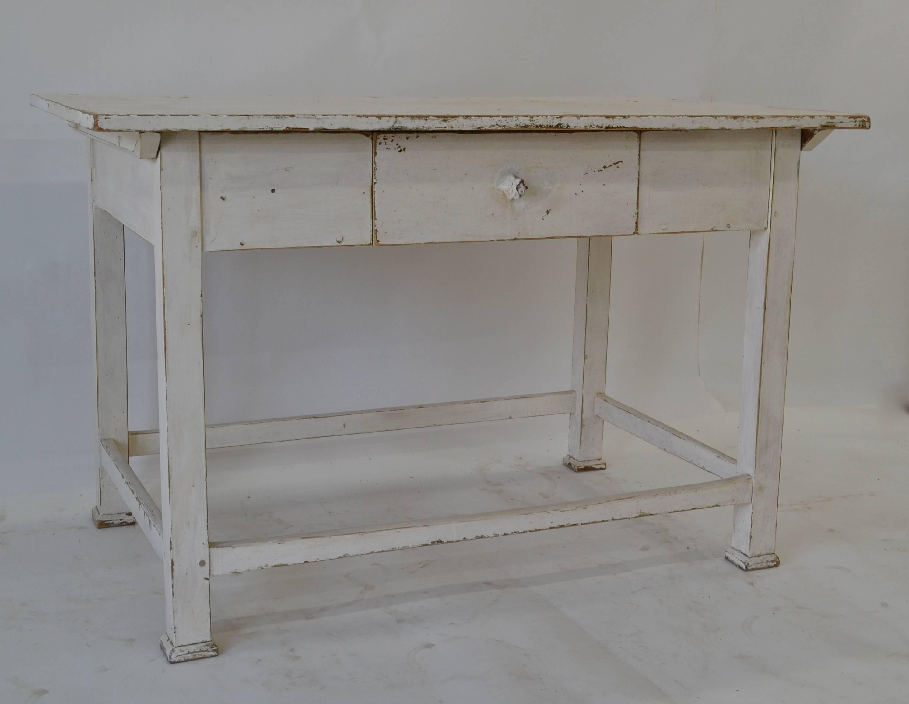 A sturdy pine work table with a single deep hand-cut dovetailed drawer. Four square legs are joined all round with nicely worn stretchers. All pegged construction and in old white paint, worn through in parts to original green.