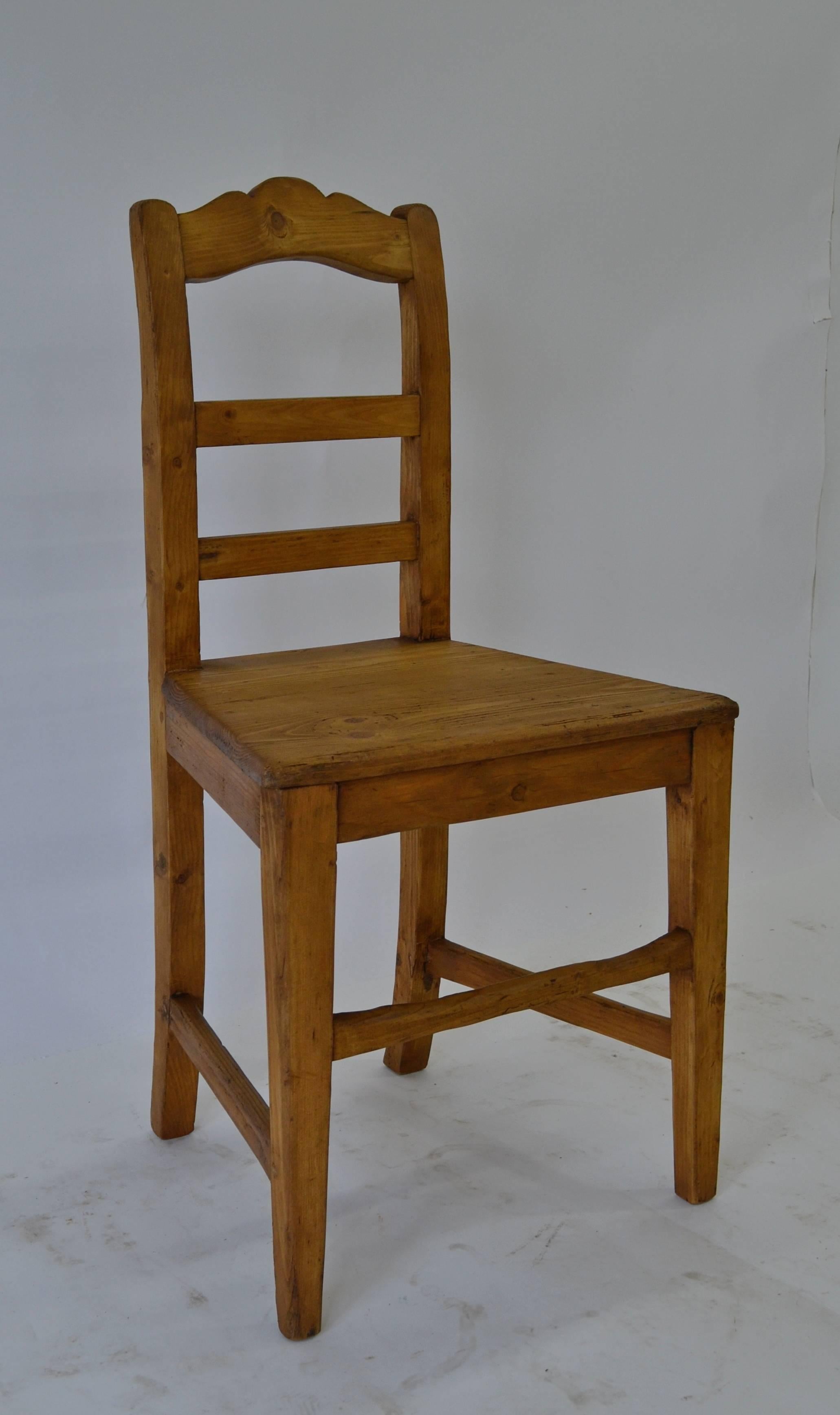 This single pine plank seat chair would be great at an antique writing table or placed in a corner to bring to the table when an extra seat is needed. A boldly arched and scalloped top rail sits above two plain rungs. The two board seat is softly