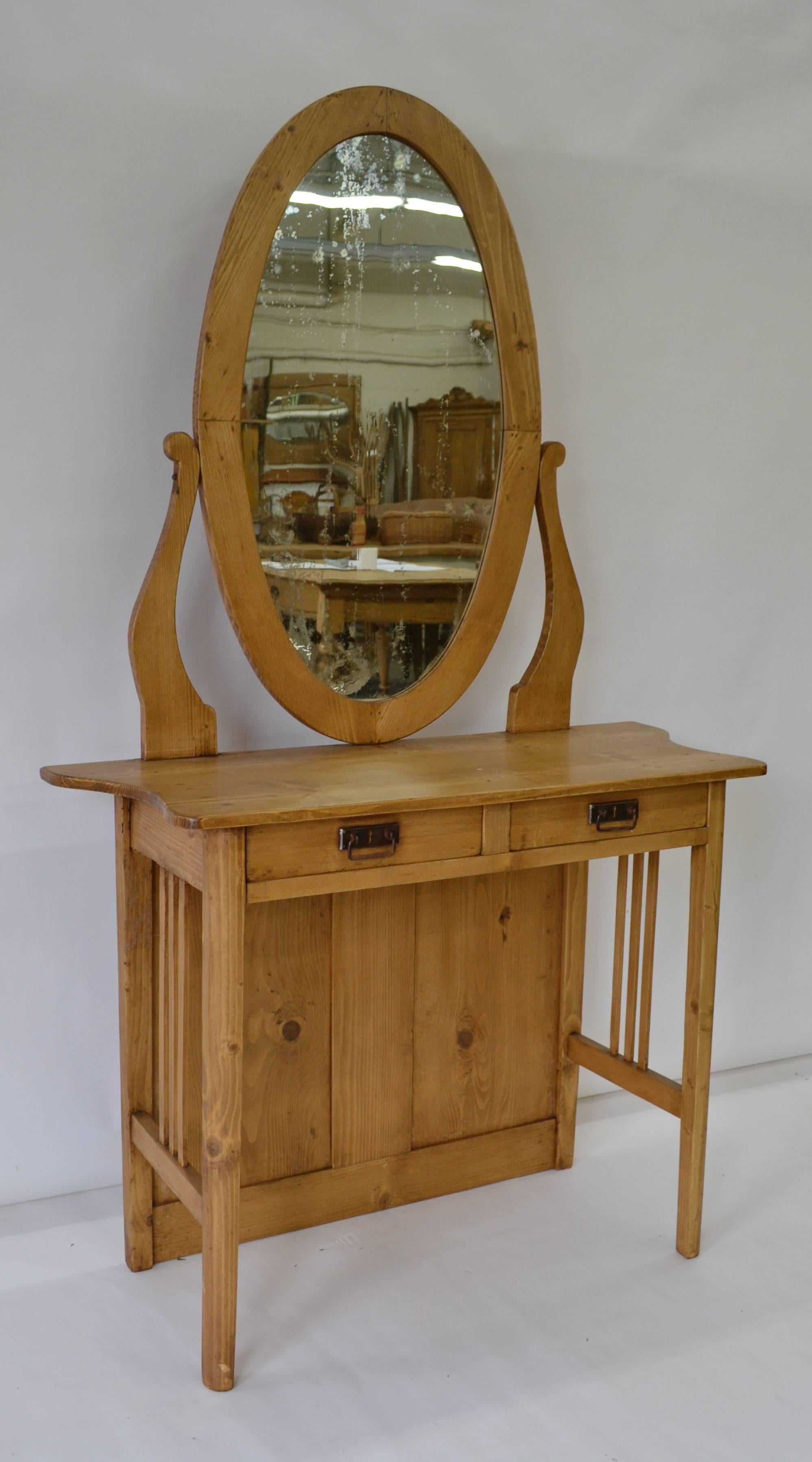 This pretty little dressing table features an oval mirror with original, rather distressed, glass, which pivots on lyre-shaped supports. The shallow top combines a straight front with serpentine sides and there are two full depth hand-cut dovetailed