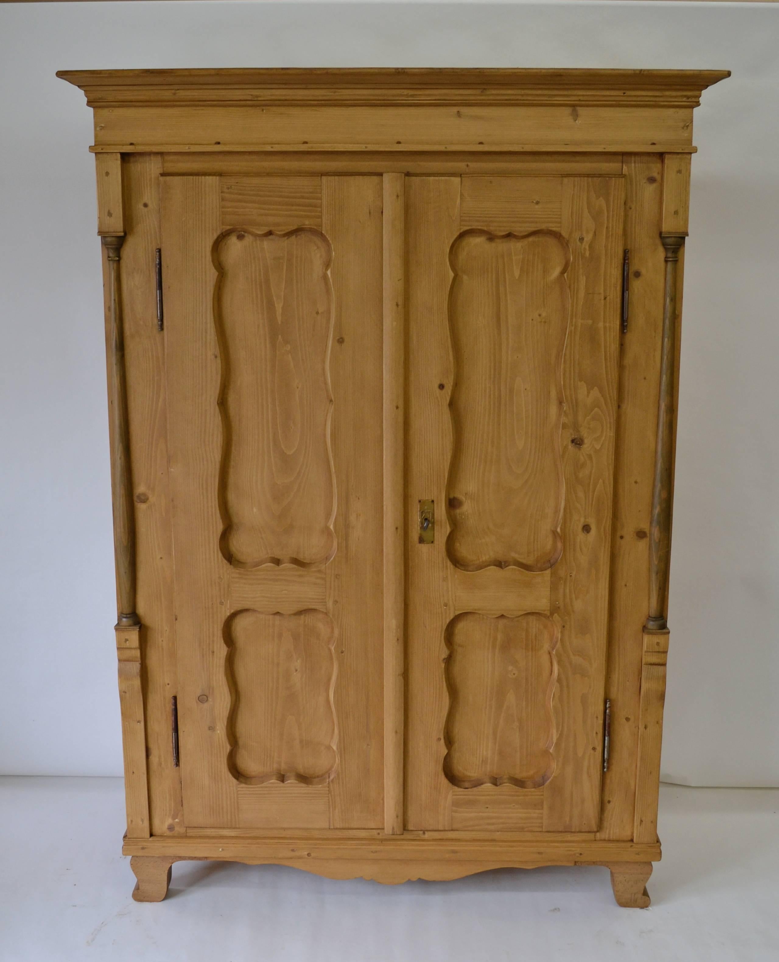 This is a small two-door pine armoire of exceptional quality, superb condition and unusual design. Constructed of stock one inch thick, this sturdy piece features eight scalloped panels in the doors and sides. The doors open almost 180 degrees on