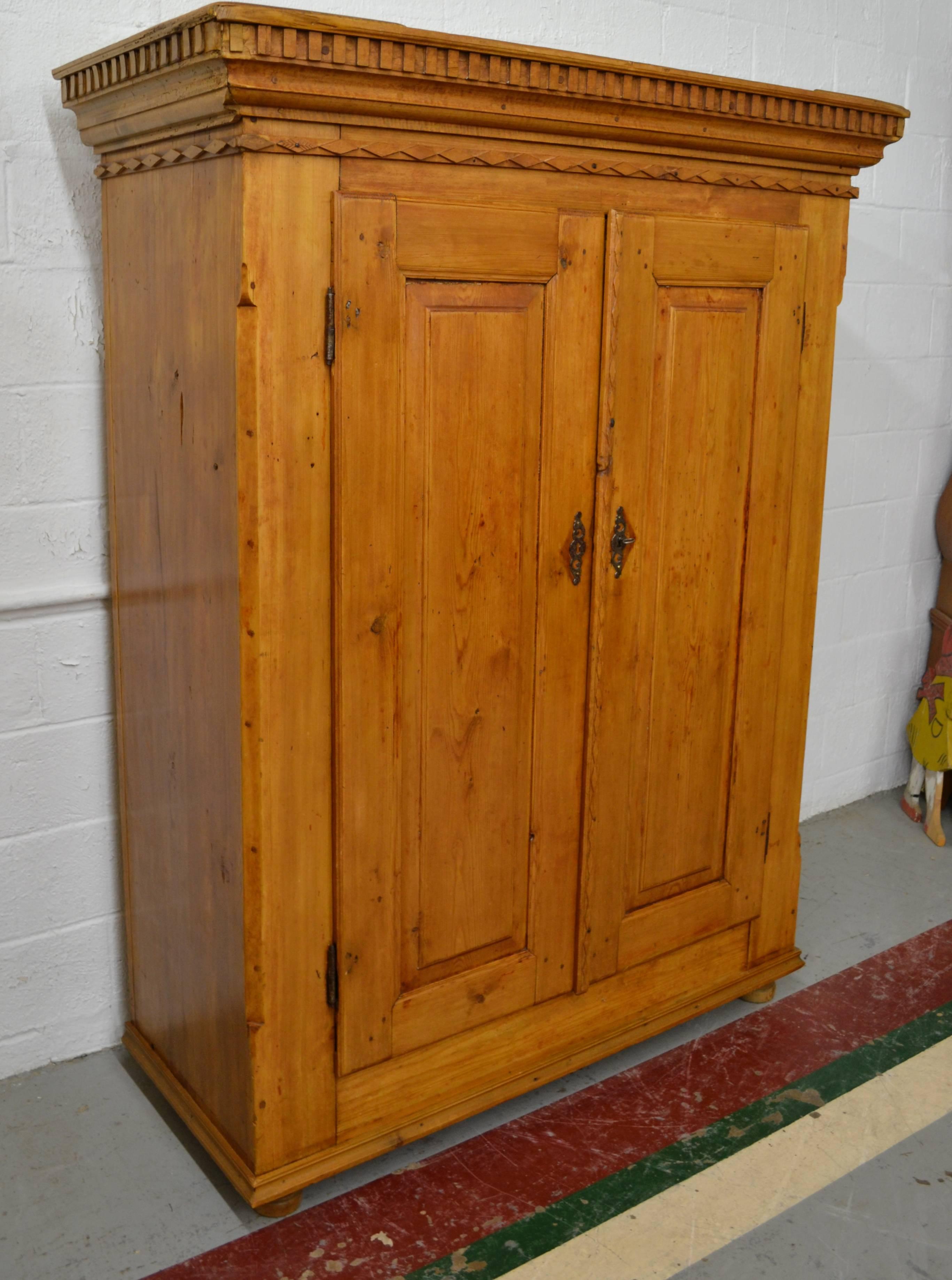 This outstanding heavy and sturdy armoire, built from stock over 1” thick, features a bold hardwood crown with hand-cut dentil molding sitting above a hand-cut trim of laterally-laid diamonds. Two raised panel doors open wide on fiche hinges and