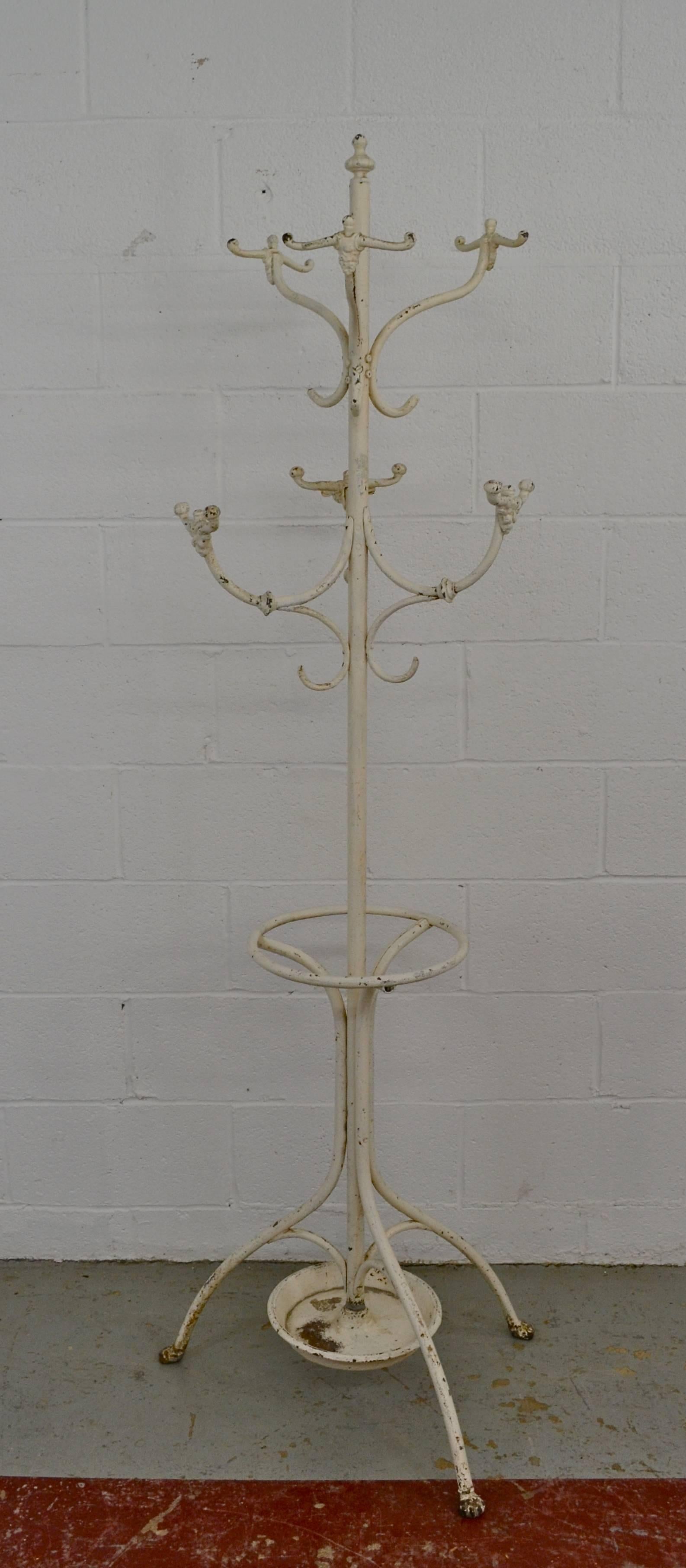 A nice example of the classic central European halltree in wrought and cast iron. Six anthropomorphic double hooks with single hooks trailing are bolted to a tubular column mounted by a decorative iron finial. A circular tube holds wet umbrellas