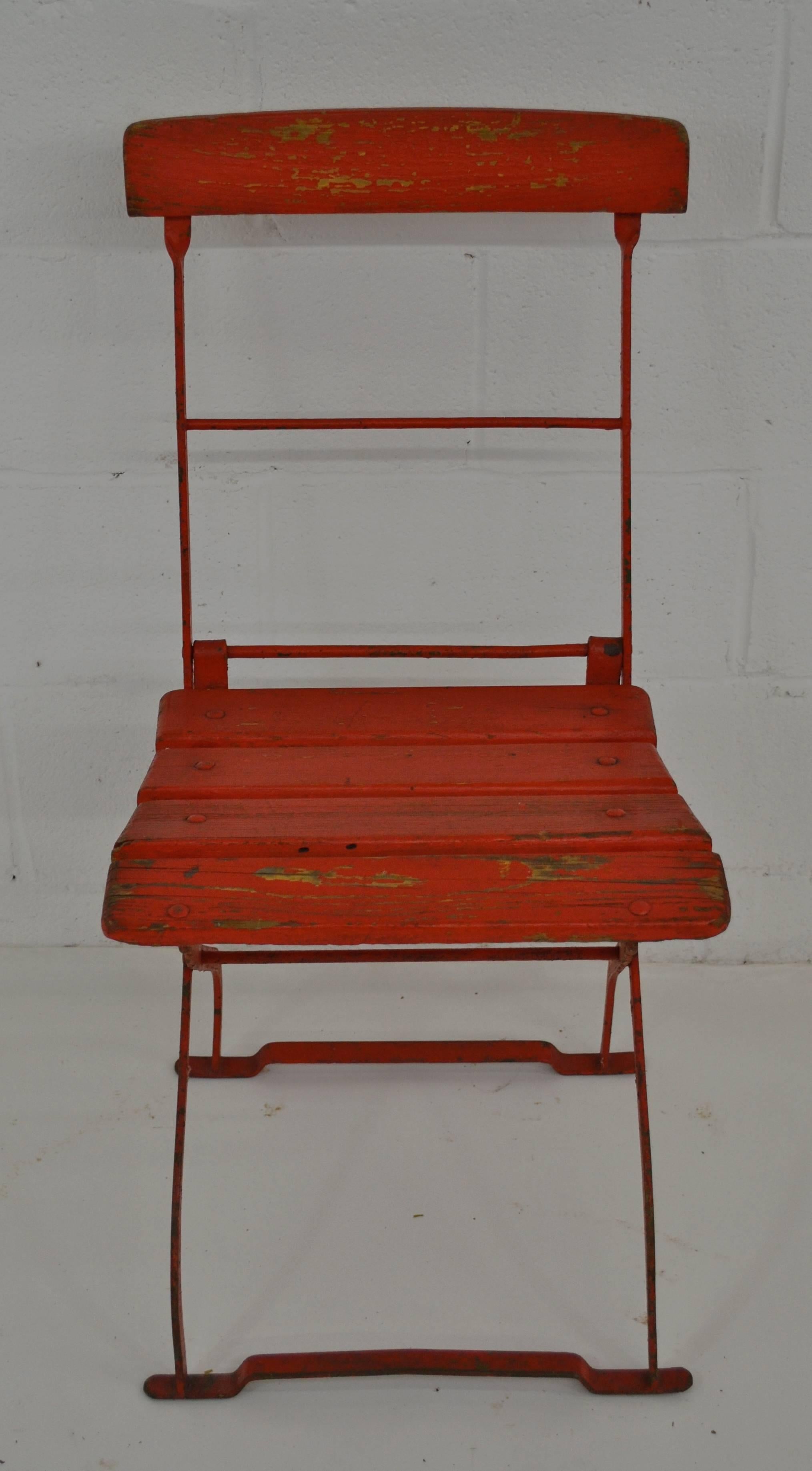 A wrought iron folding bistro chair with oak back rail and seat slats, by F. Schmidt of Elsterberg, Germany. In old very worn red paint on original green.