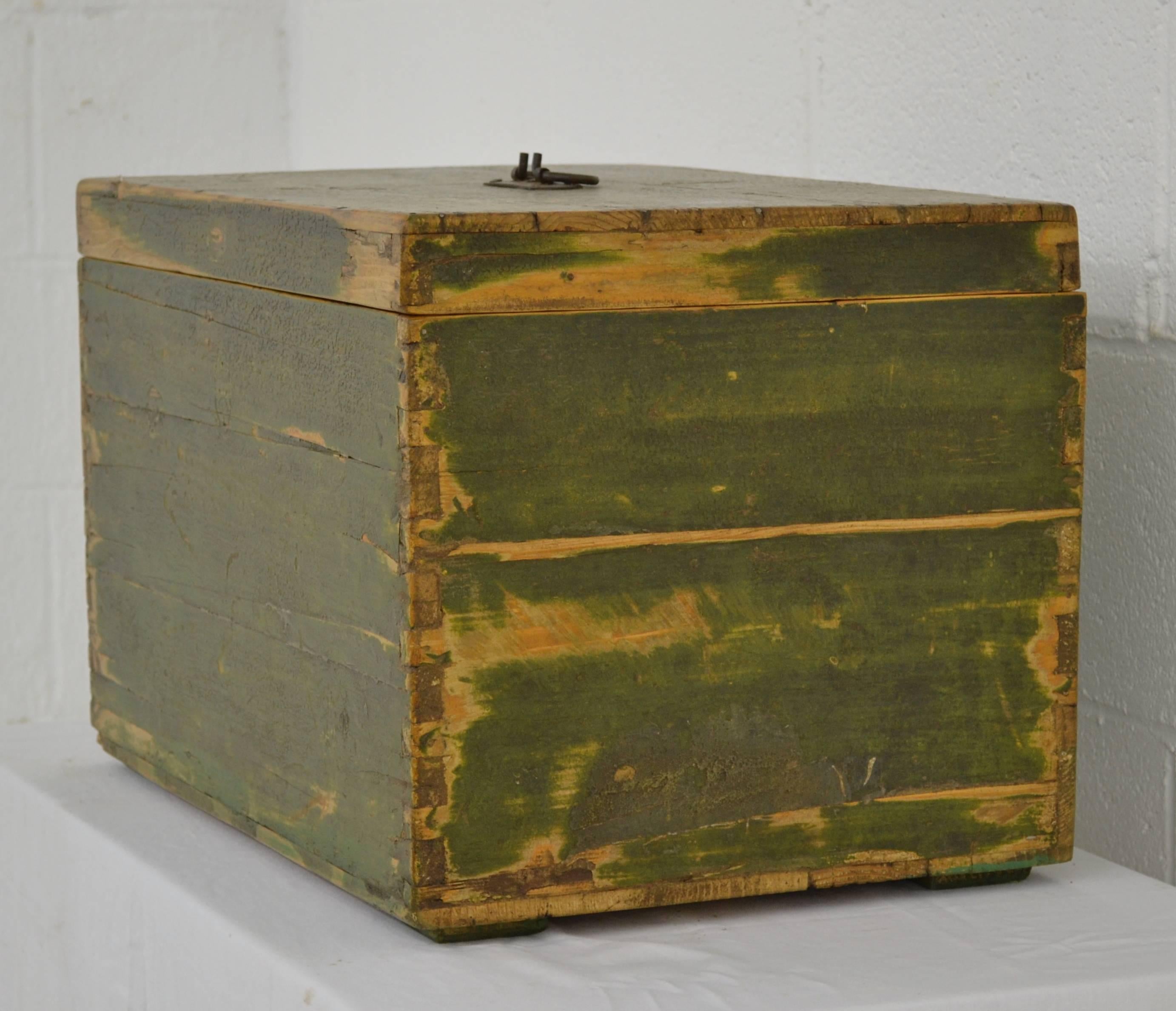A vintage pine dovetailed army box with a wrought iron handle. In well-worn old green paint.