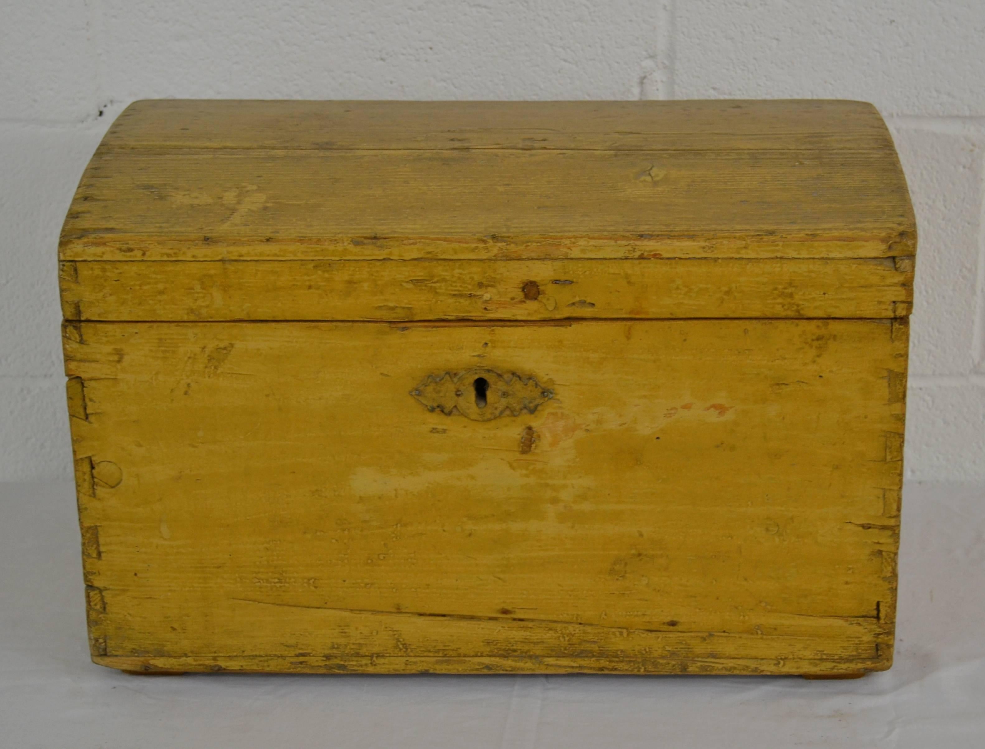 A vintage pine dovetailed army box with a stamped zinc escutcheon plate and slight dome to the top. In old worn yellow and mustard paint.