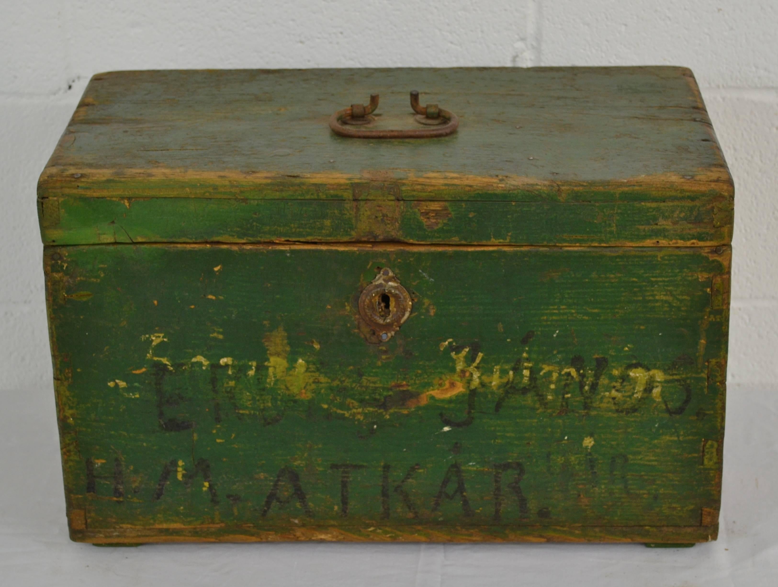 A vintage pine dovetailed army box with a wrought iron handle and pressed zinc escutcheon plate. Three names painted on the front reflect changes in ownership. In shades of old worn green paint.