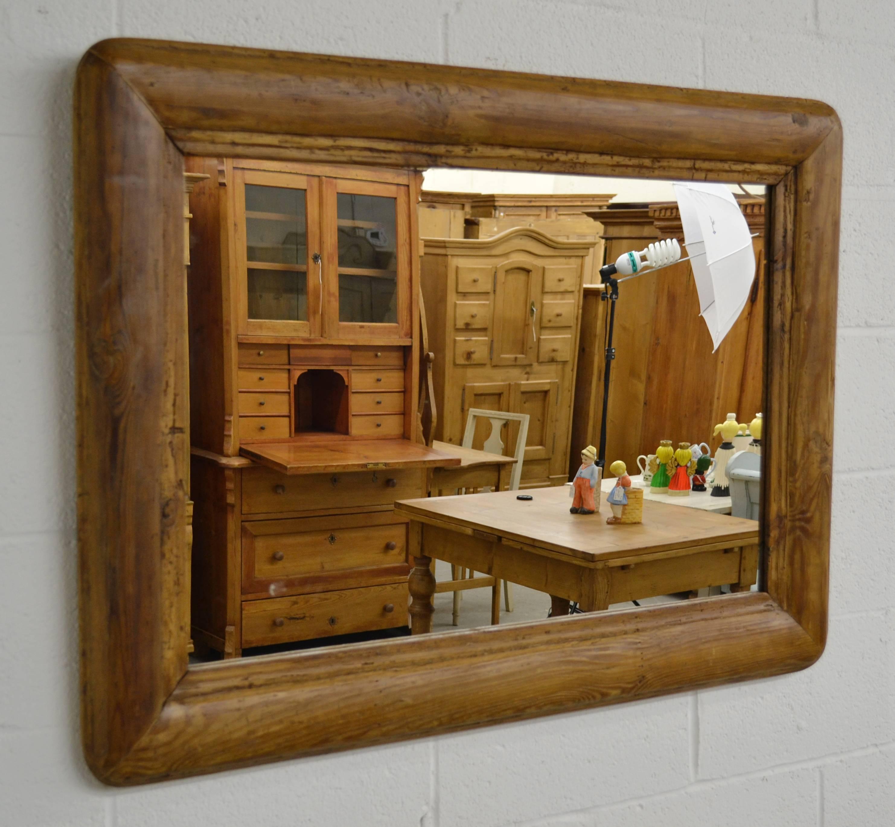 A large and bold antique pine frame almost 5” thick, with strong grain pattern and rounded corners, is fitted with new mirror glass in this handsome piece. Finished in rugger brown paste wax.