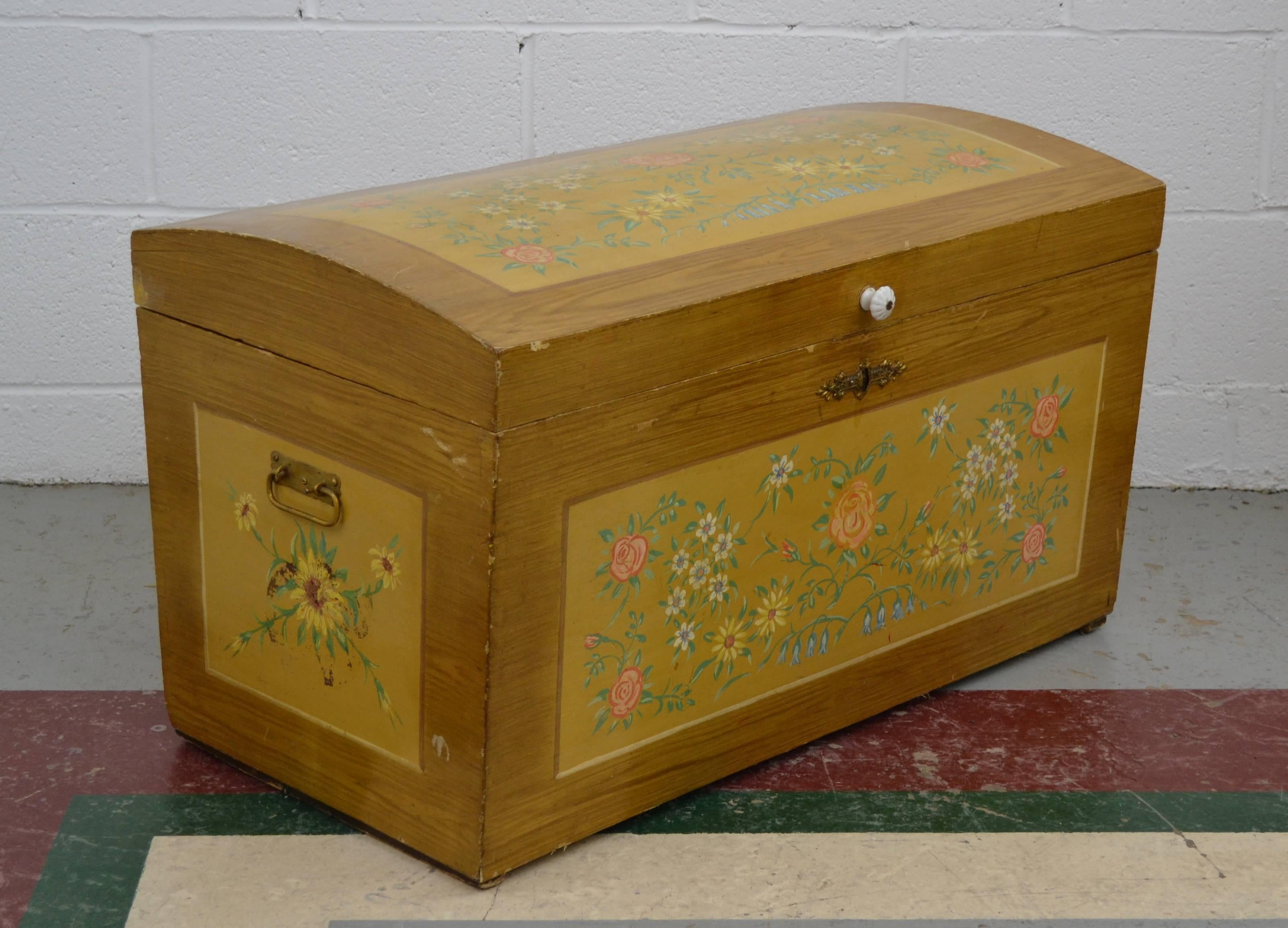 A lovely small pine dome top trunk of hand-cut dovetailed construction, hand-painted all-over in a light brown grain paint with floral decorated faux panels on the top and on three sides. The paintwork has a clear varnish finish and so has remained