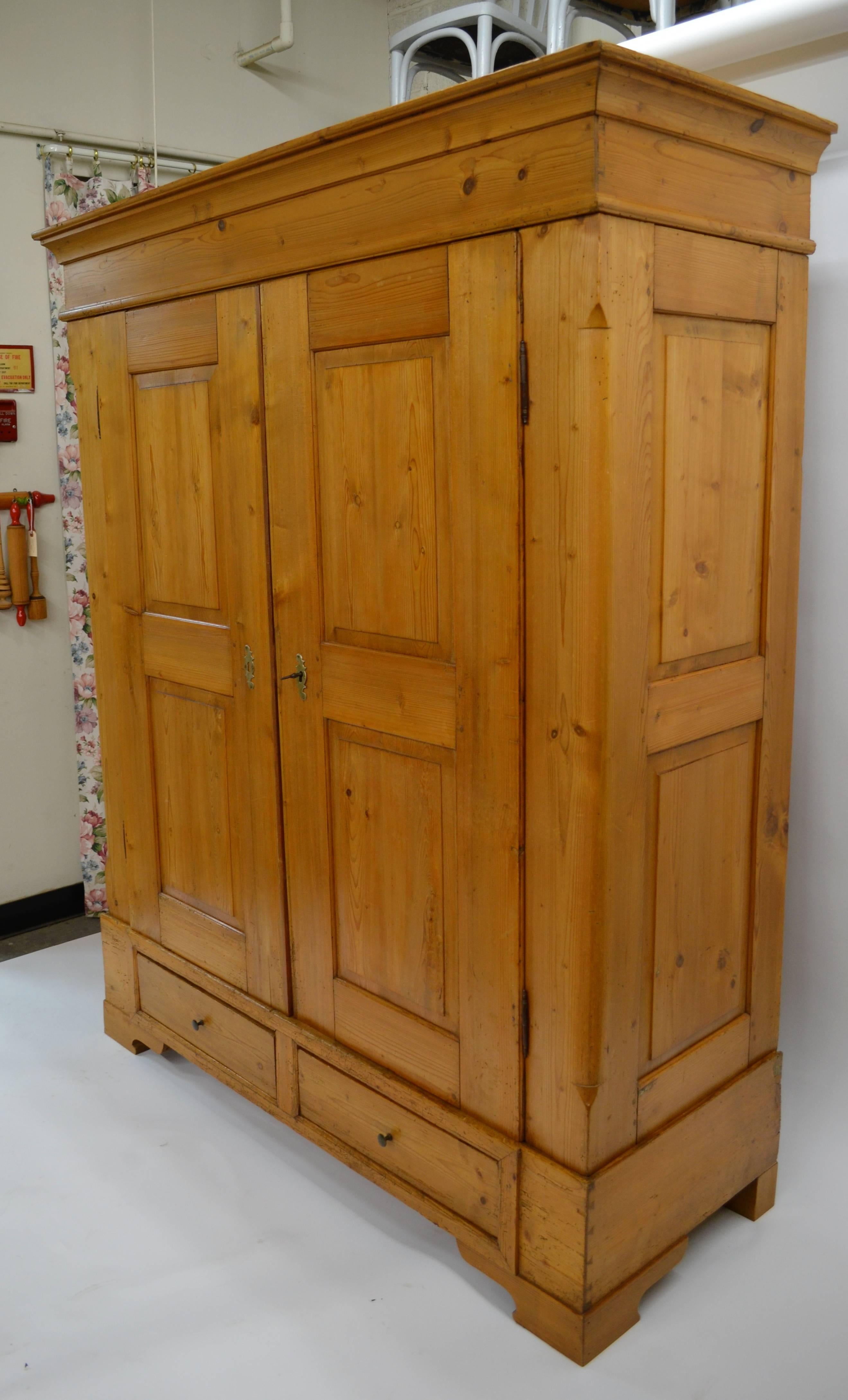 A rather plain but very distinguished eight panel pitch pine armoire from Denmark. The boldly swept crown sits above two raised panelled doors, which open to 180 degrees on fiche hinges. The notched and gently rounded front corners lead the eye to
