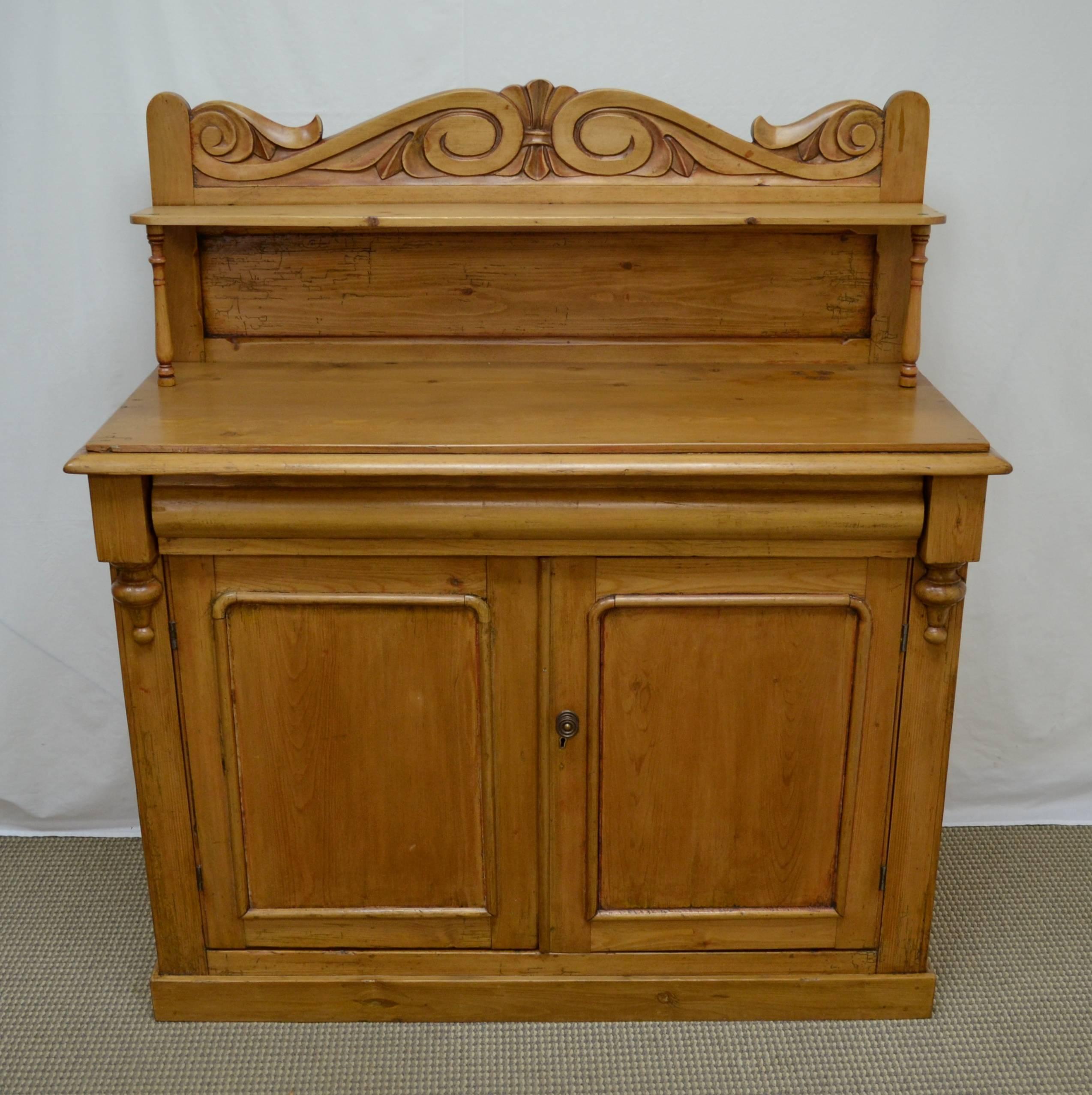 This is a charming little country chiffonier. The pine base features two paneled doors opening to a generous interior, divided by a single original shelf. The front corners have unusual split baluster and block corbels, flanking a long hand-cut