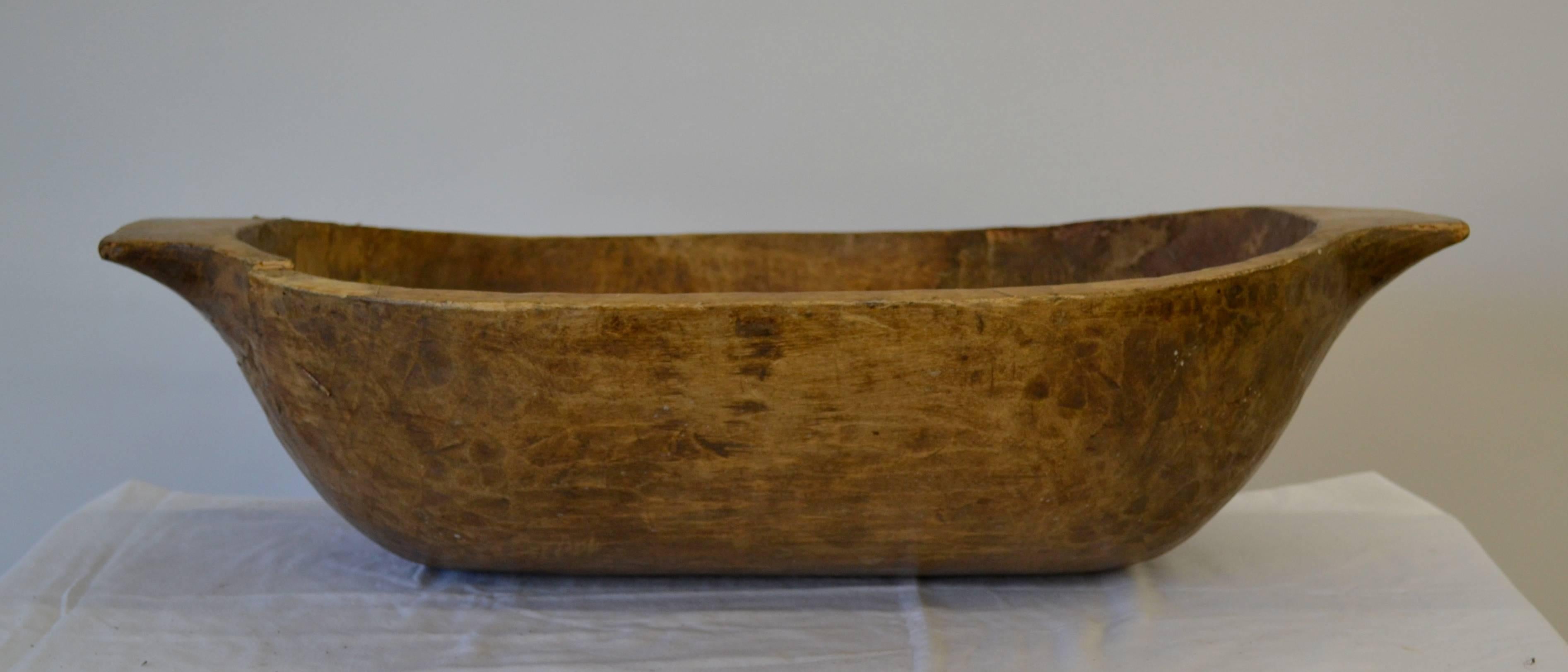 An attractive antique dough bowl or trog, hand-carved from a split log.  Great as a centerpiece or as a catch-all by the door to toss in scarves and gloves, or use for keeping kindling, logs, or magazines by the fire. 